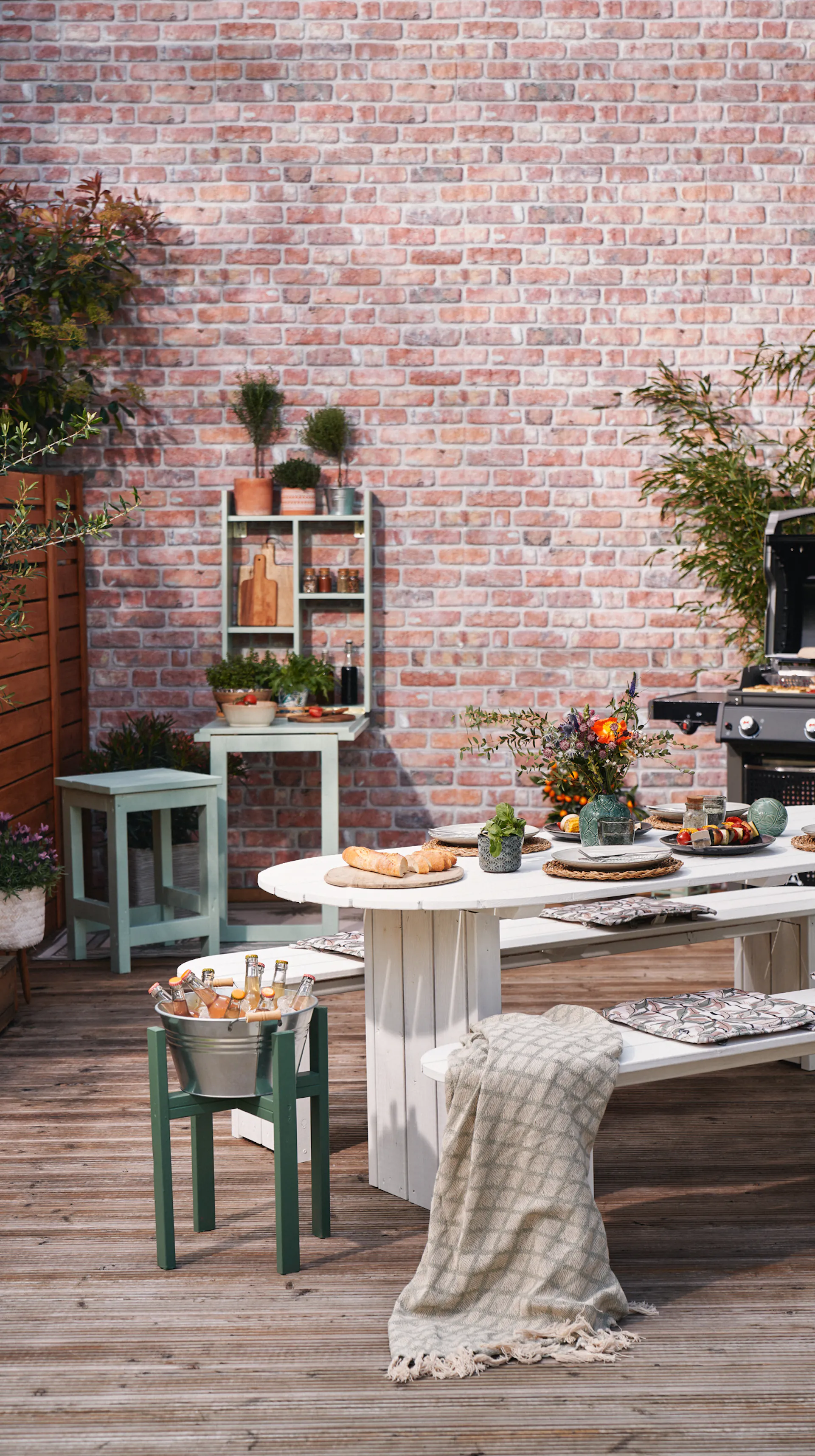 Rozložený grilovací stůl s prostřeným stolem v popředí