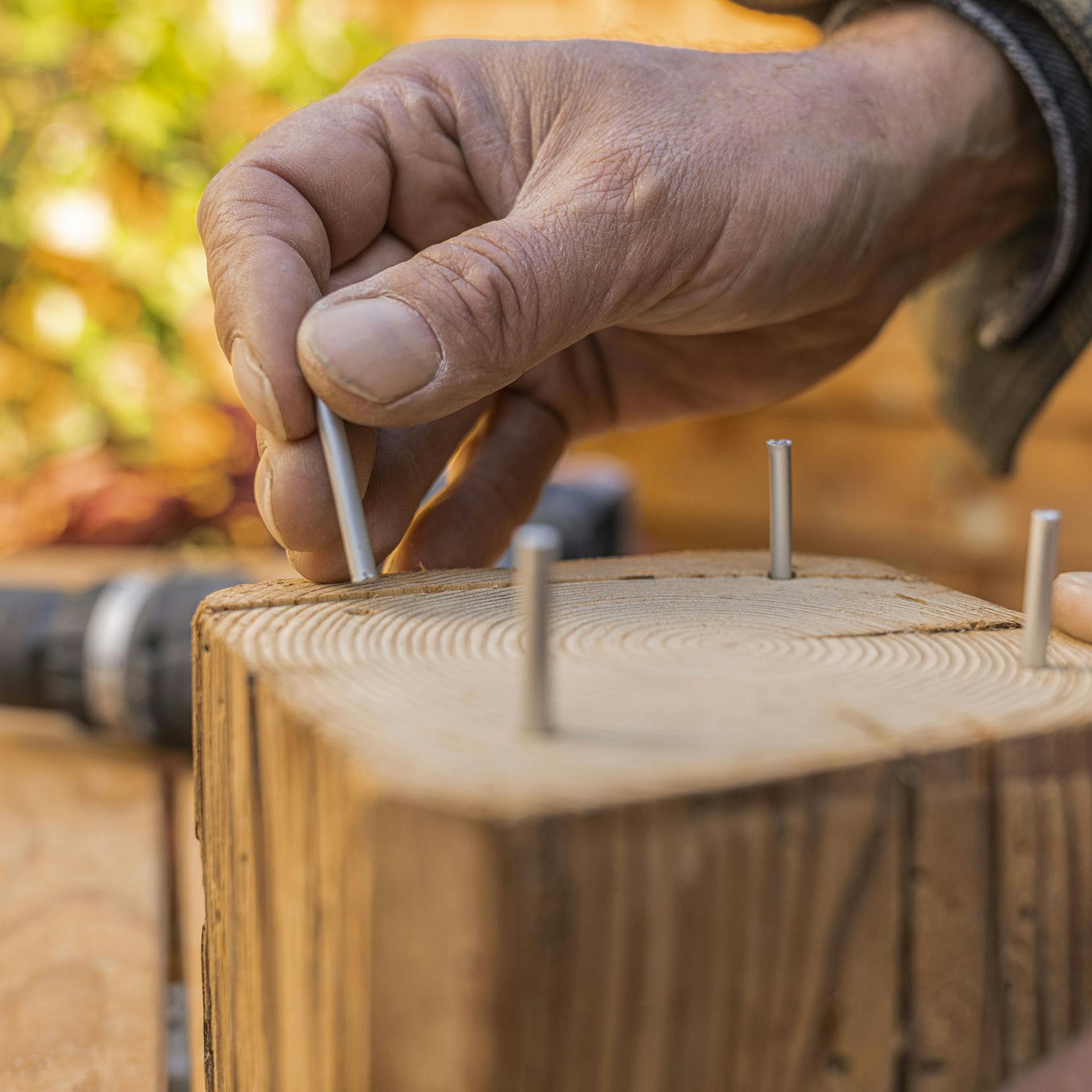 A férfi alumíniumlábakat illeszt a törmelékfa aljába.