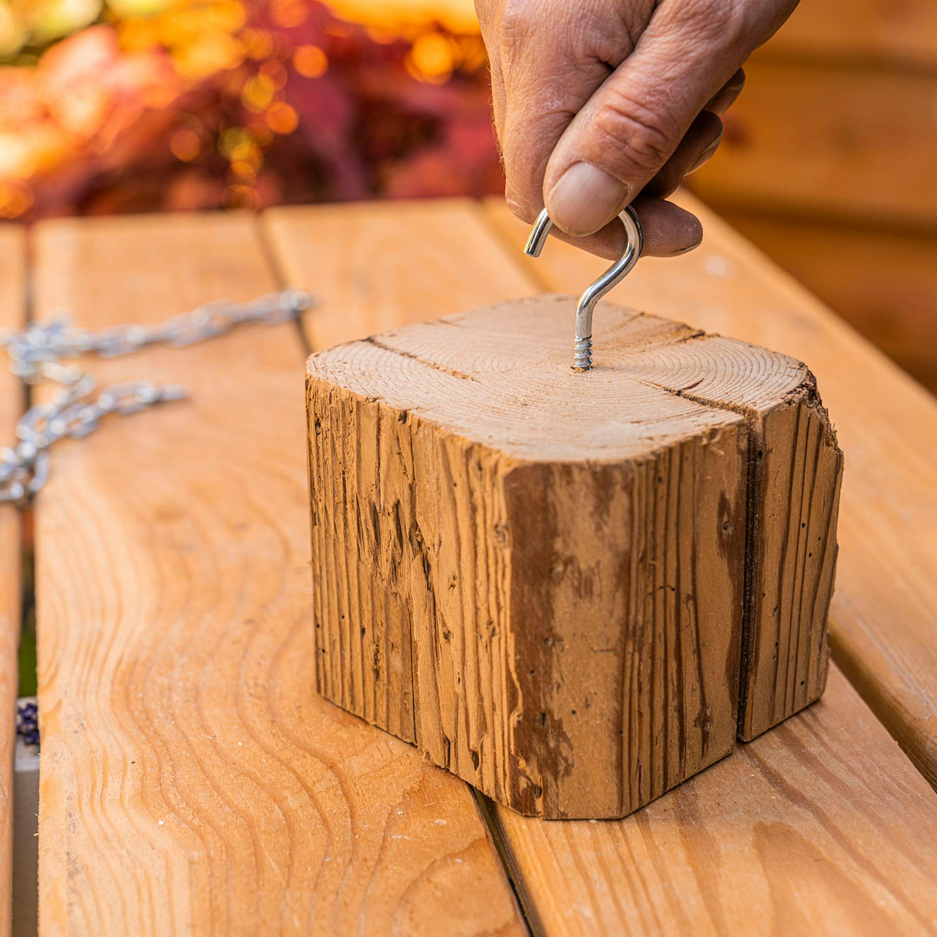 A férfi egy csavarkampót forgat a régi fagerenda fedelébe.