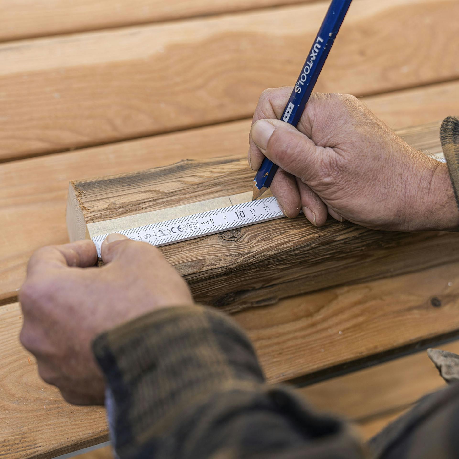 A fára ragasztott maszkolószalagon bejelöli a pontokat a férfi.