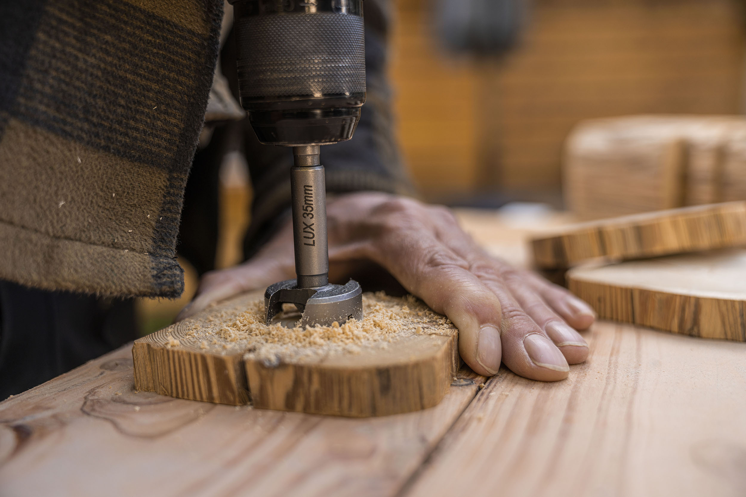A férfi egy Forstner-fúróval lyukat fúr a fakorongba.
