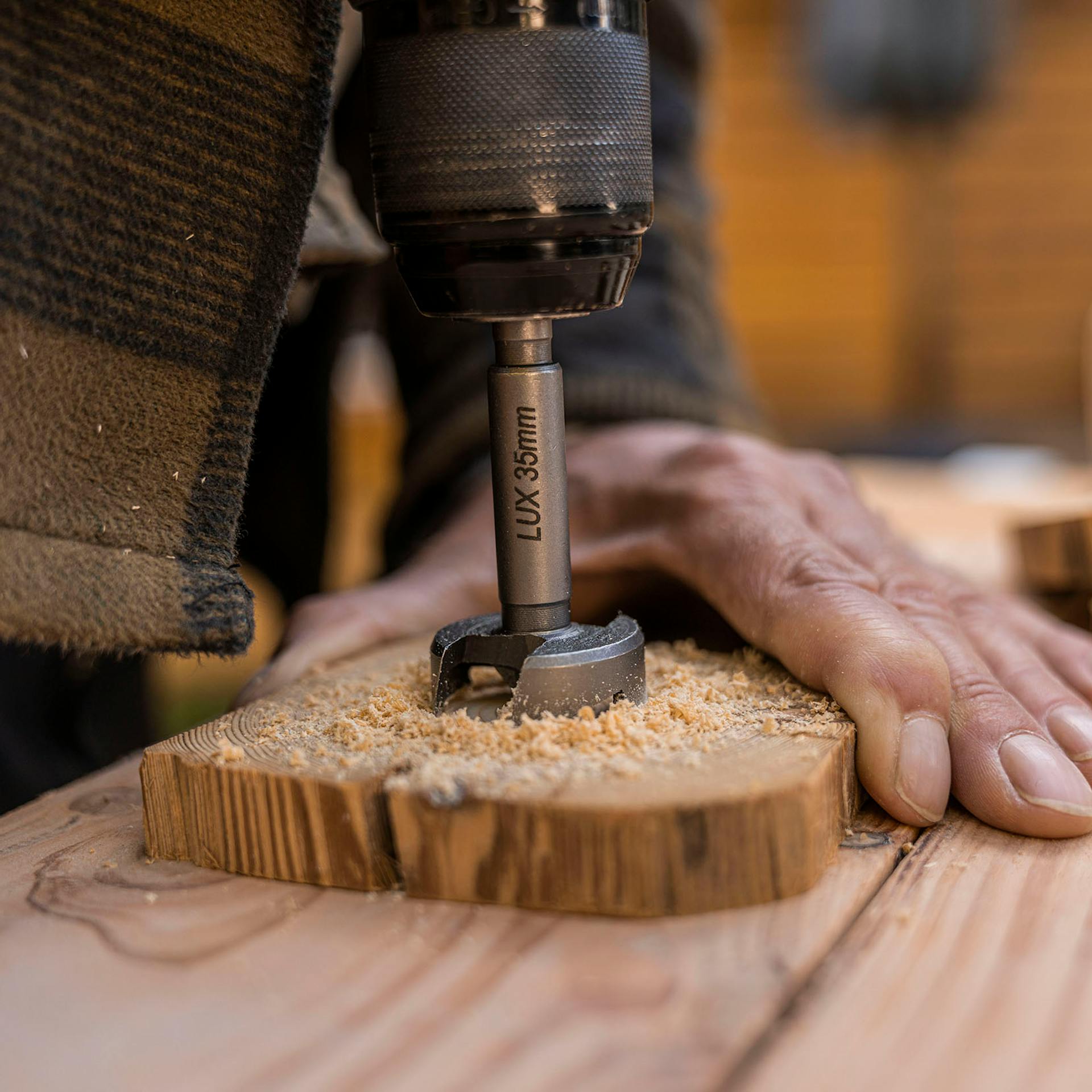 A férfi egy Forstner-fúróval lyukat fúr a fakorongba.