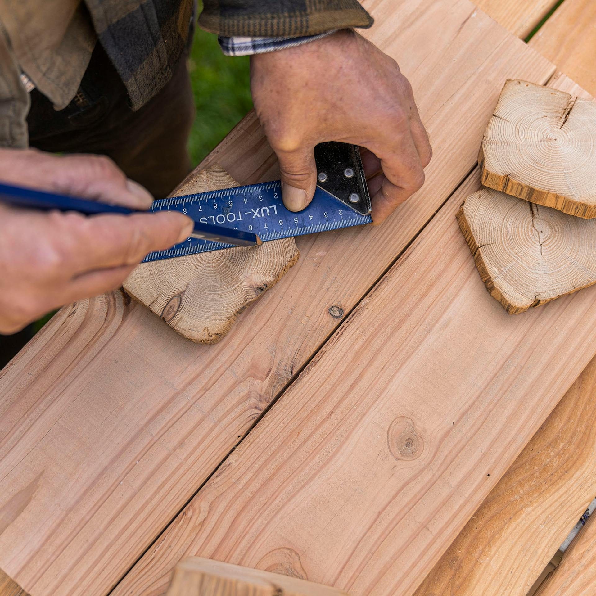 A férfi egy szög és egy ceruza segítségével megjelöli a középpontot a fadarabon.