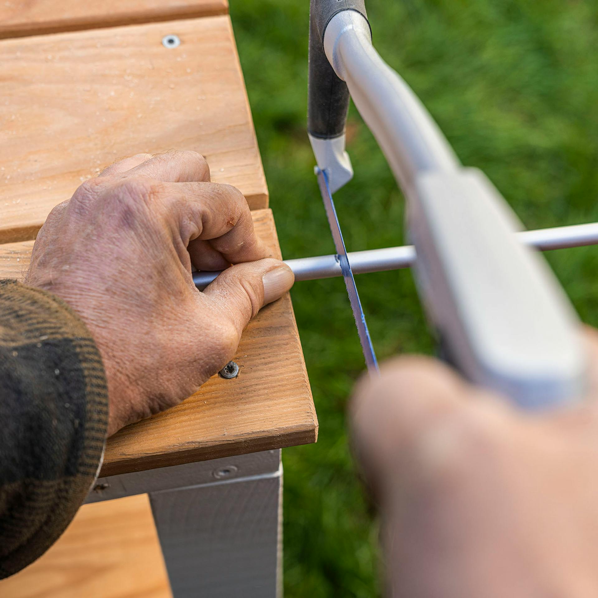 A férfi méretre vágja az alumínium kerek rudat.
