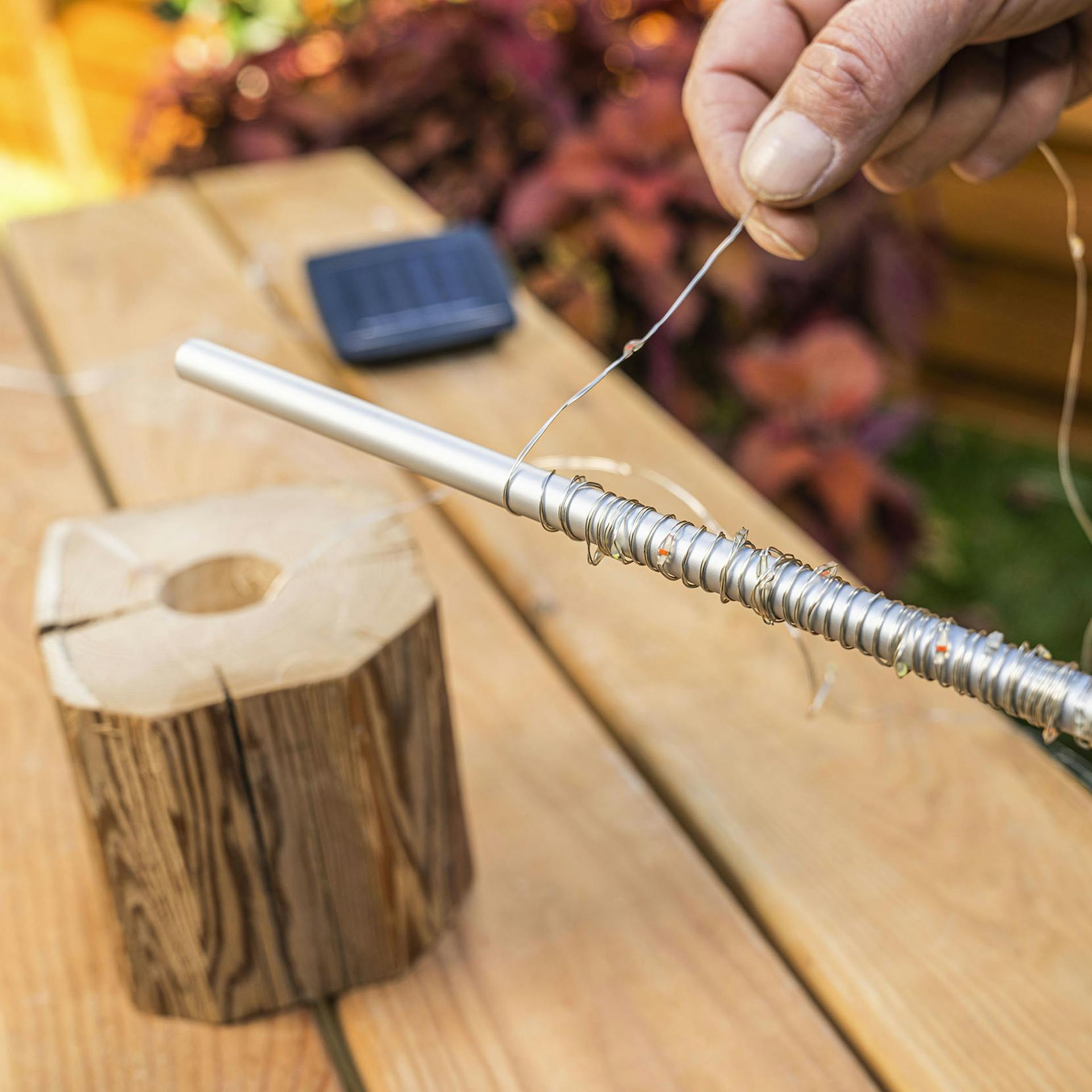 A férfi a fényfüzért az alumíniumcső köré tekeri.