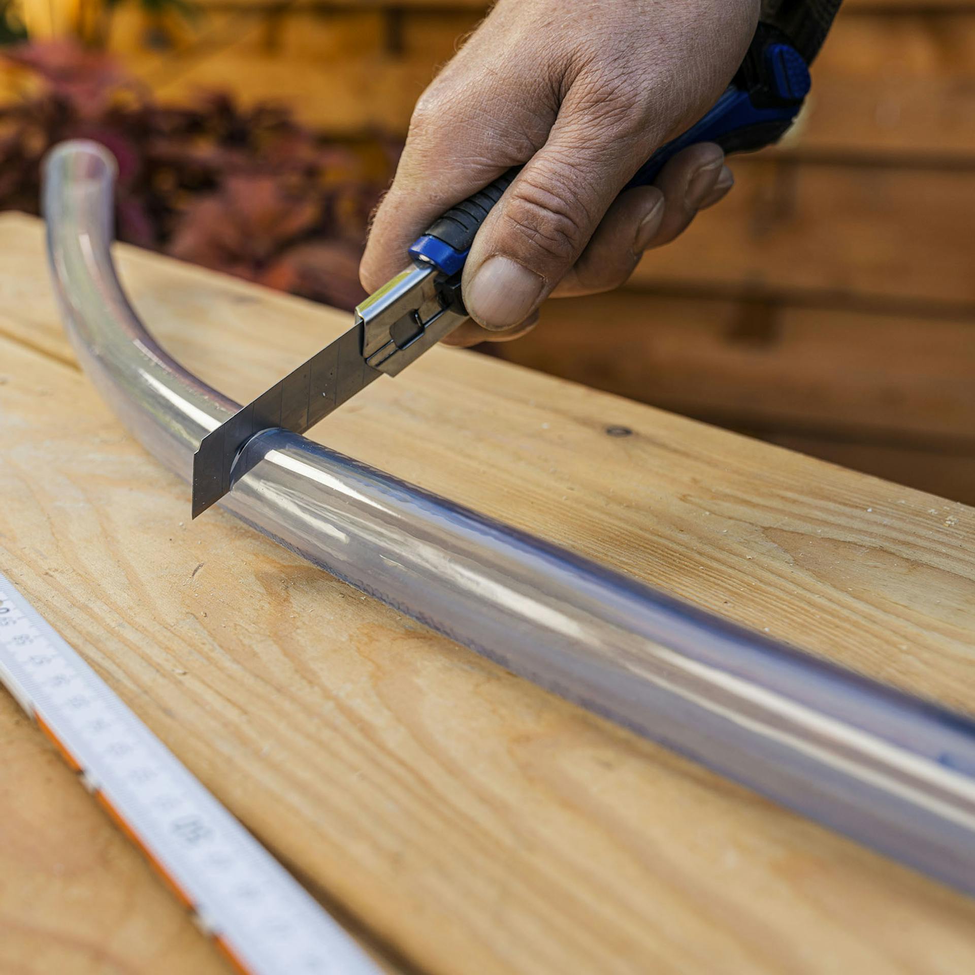 A férfi egy késsel rövidíti meg az átlátszó üvegcsövet.