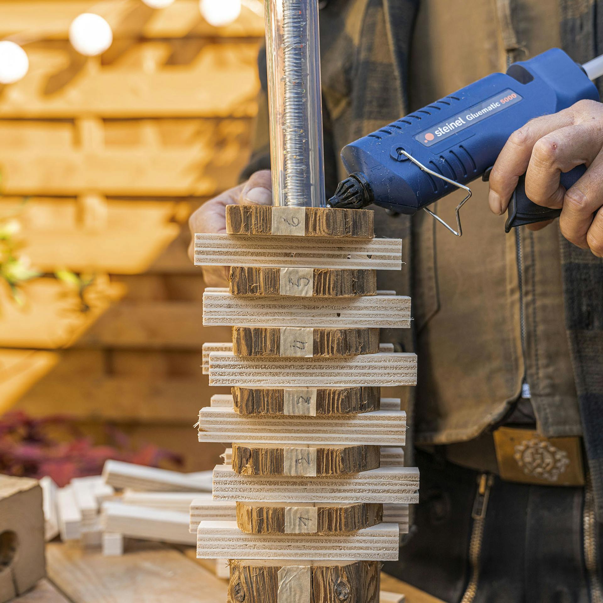 A férfi a fakorongokat a tömlőhöz ragasztja.