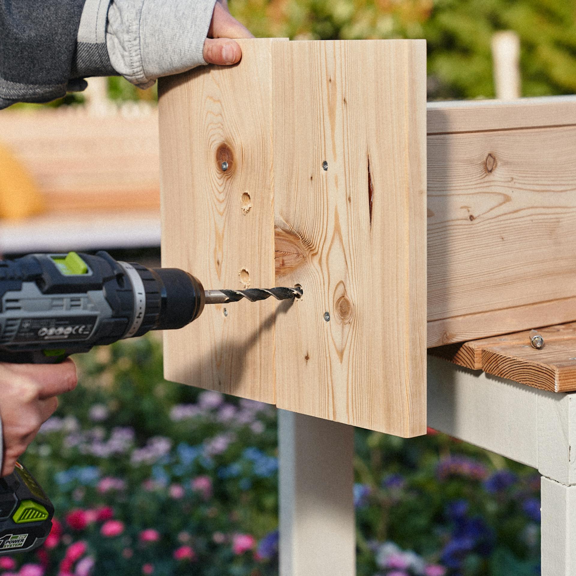 Mithilfe eines Akkubohrers, werden Ablauflöcher in den Sockel gebohrt