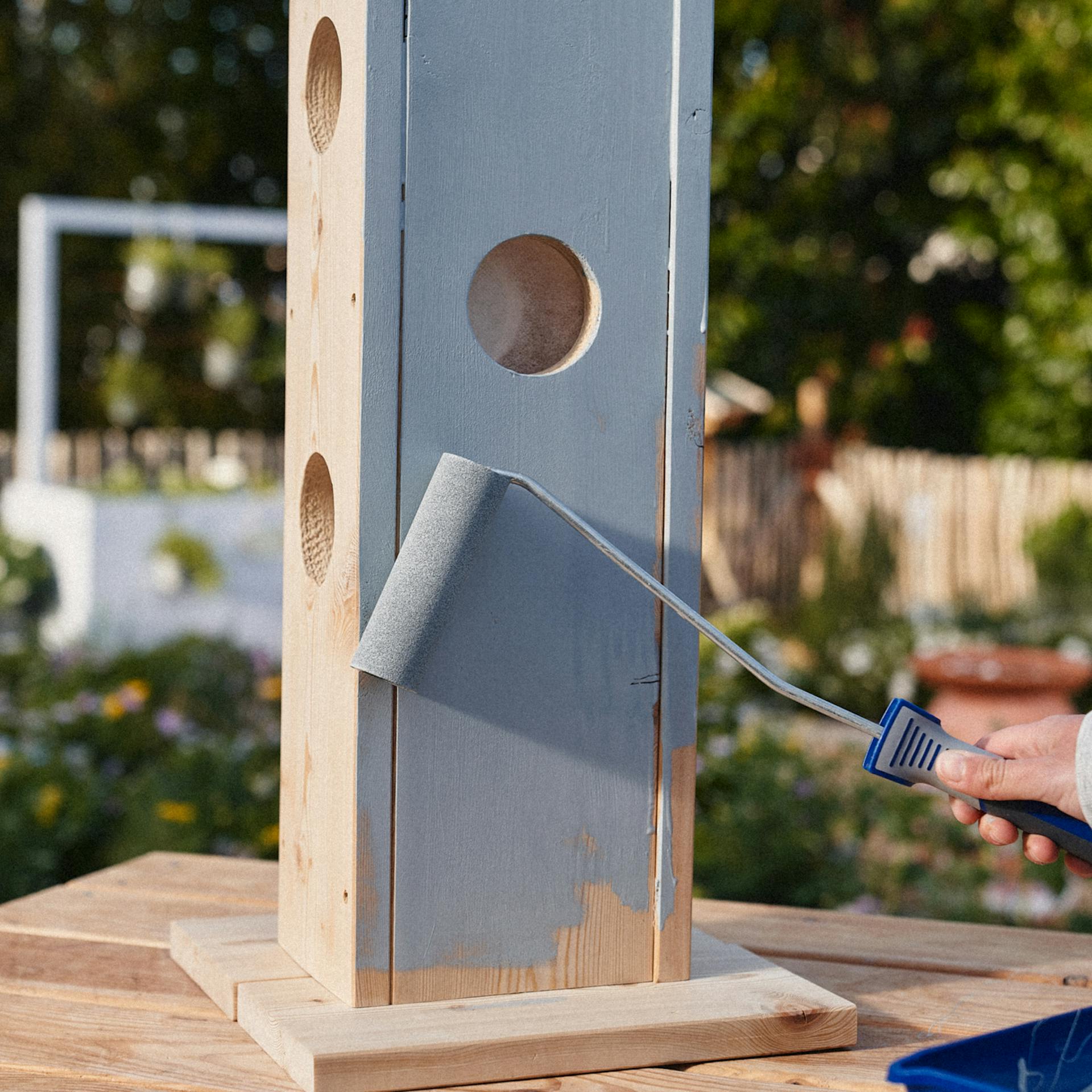 Mithilfe einer Lackrolle wird der Pflanzturm mit grauen Lack bestrichen
