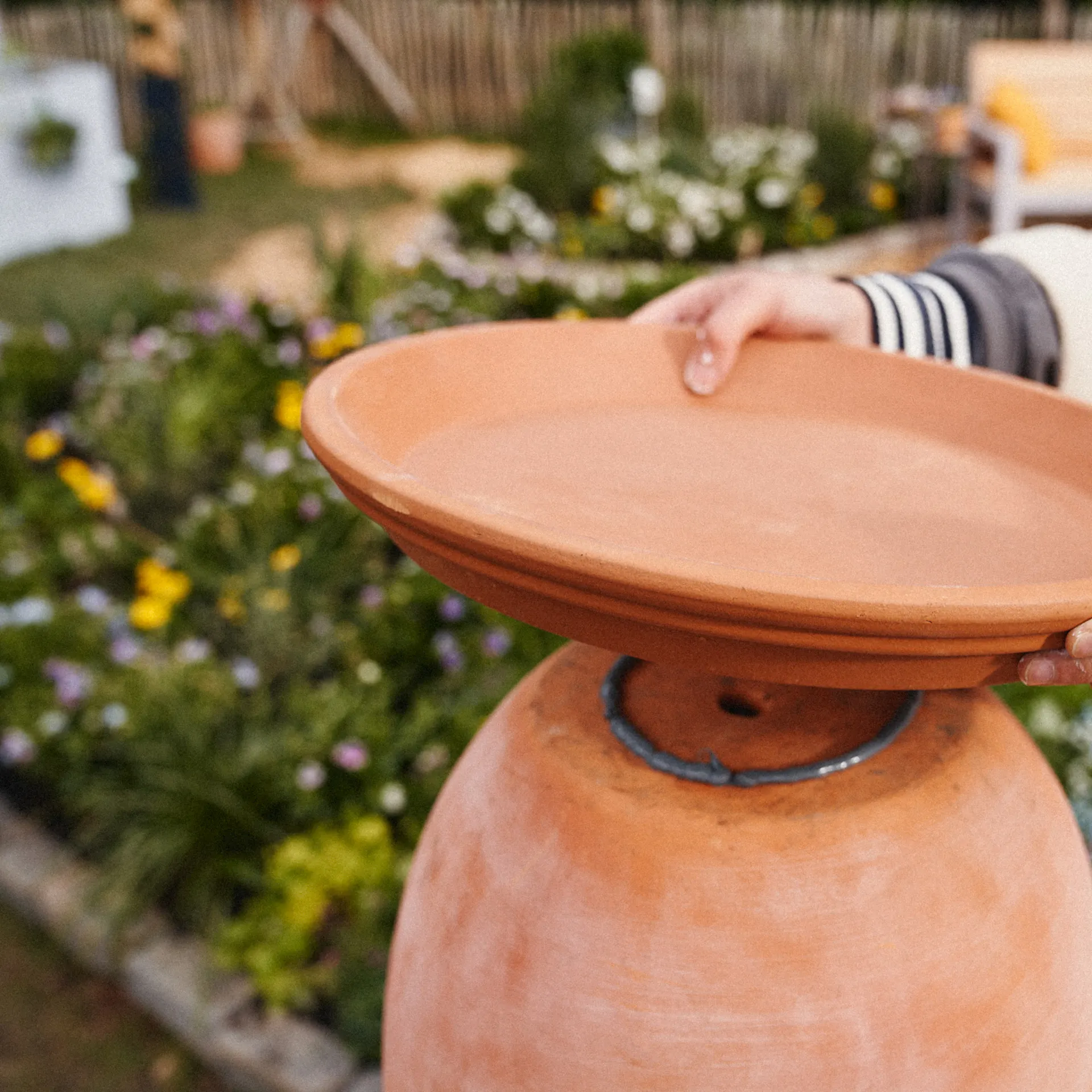Egy nő egy cserépalátétet a terrakotta edény aljára ragasztja.