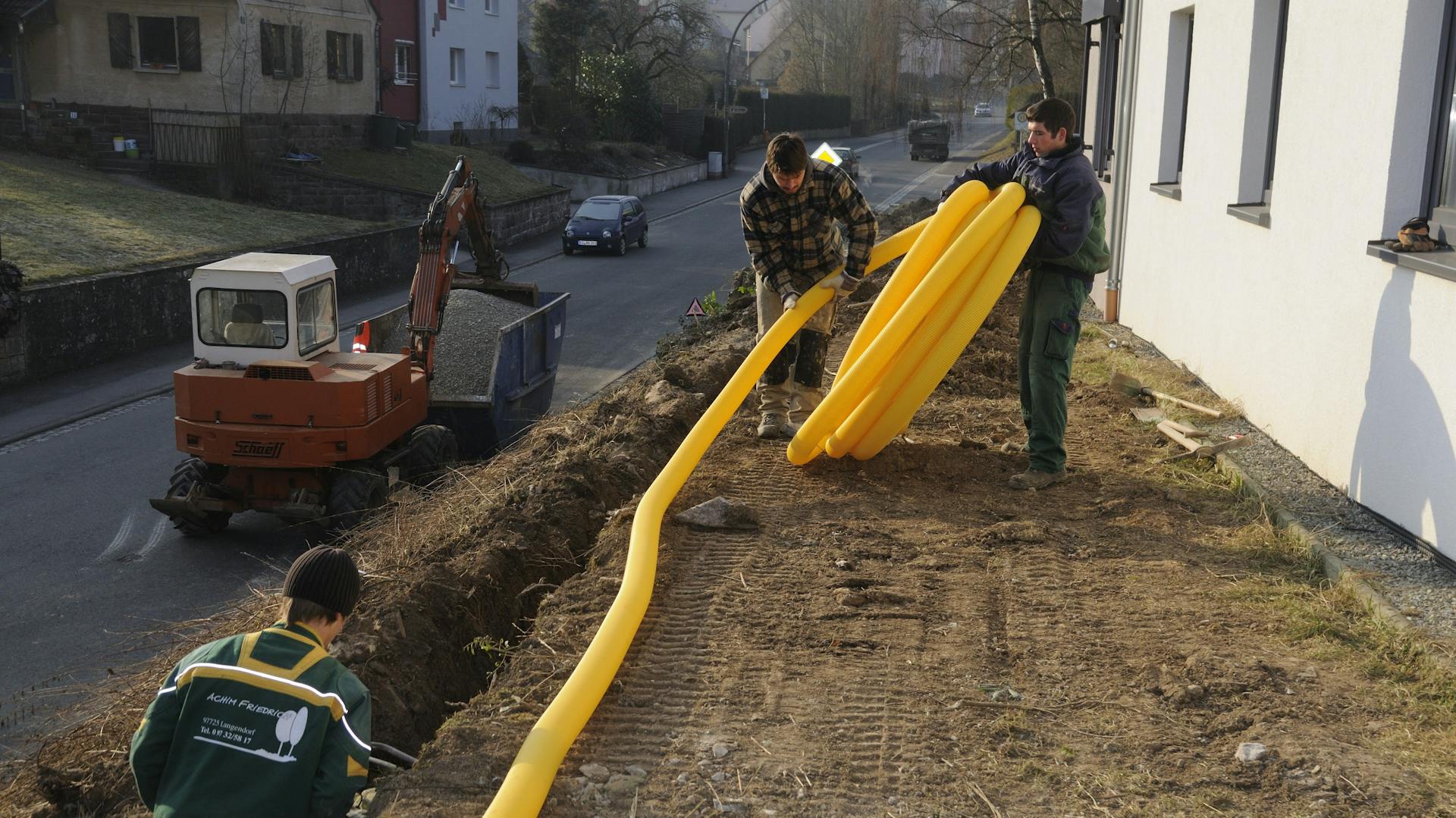 Männer verlegen ein Drainagerohr vor dem Haus