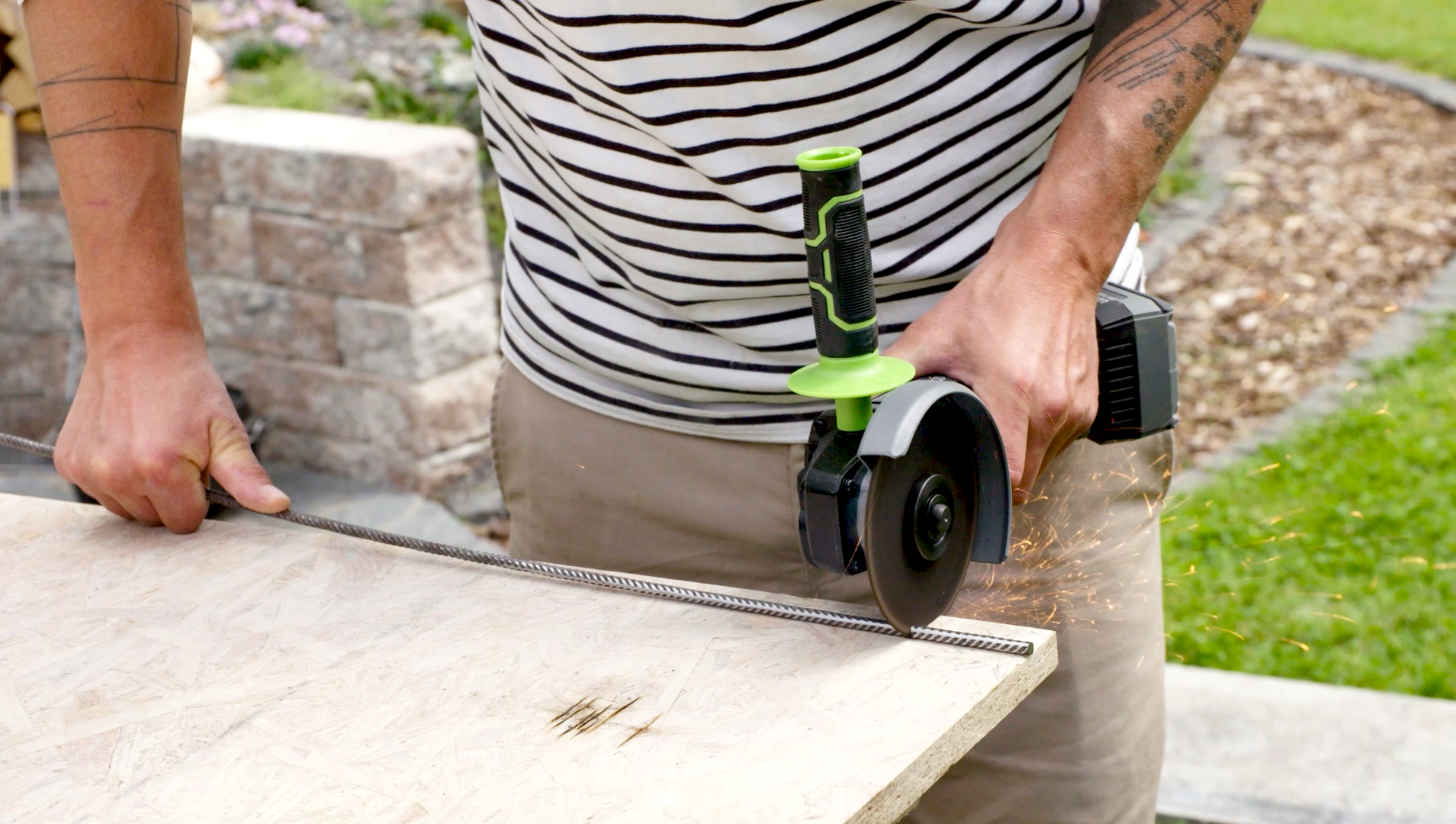 A barkácsoló férfi sarokcsiszolóval betonacélt vág méretre.