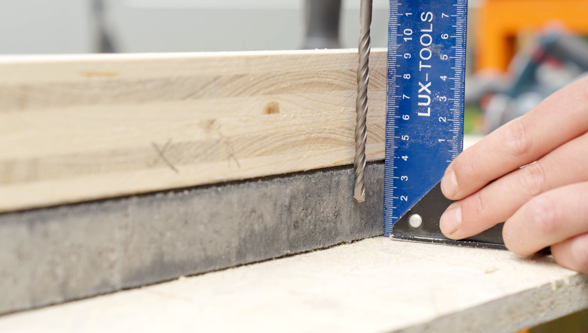 Mithilfe einer Schablone aus Holz wird eine Bohrung in eine Betonplatte geplant.