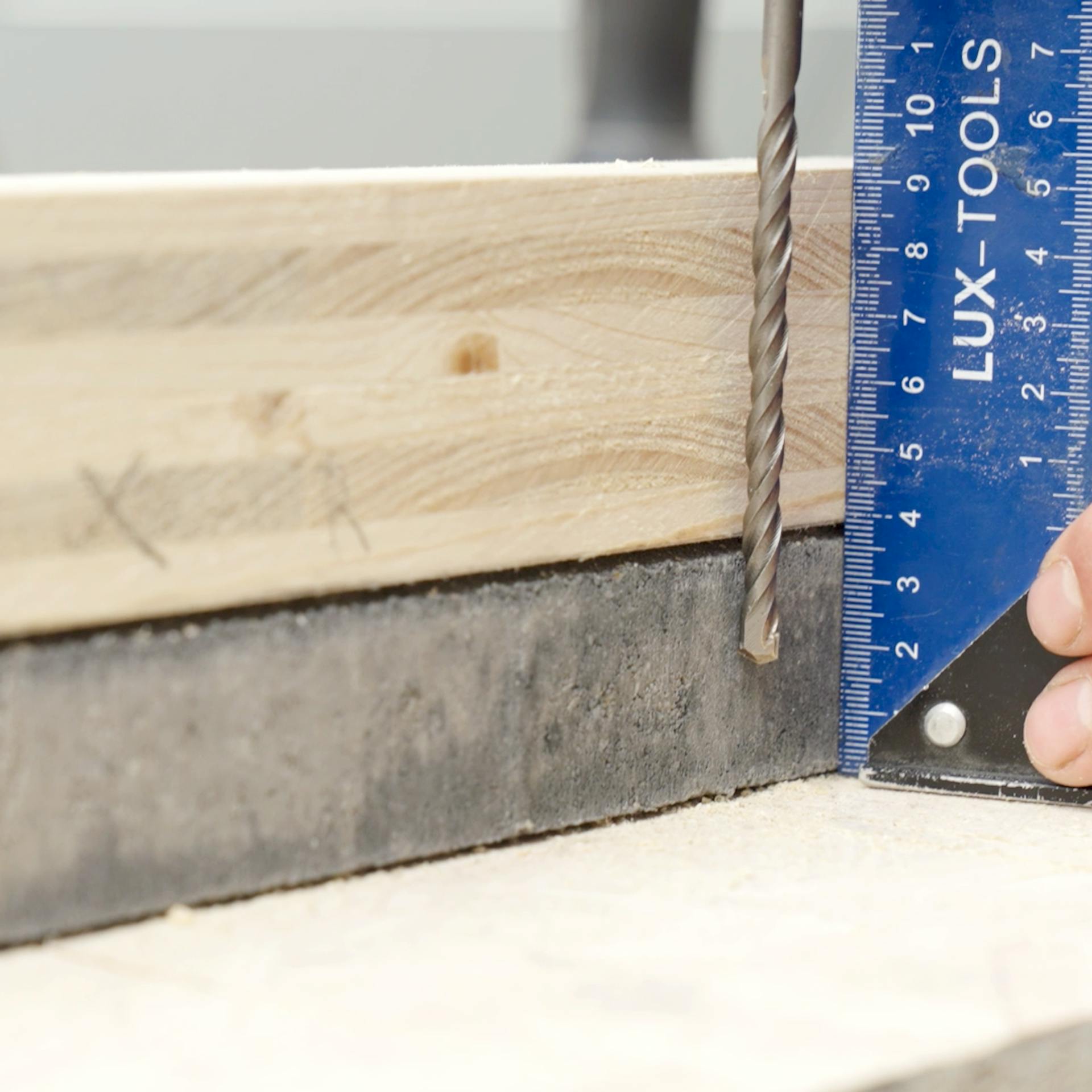 Mithilfe einer Schablone aus Holz wird eine Bohrung in eine Betonplatte geplant.