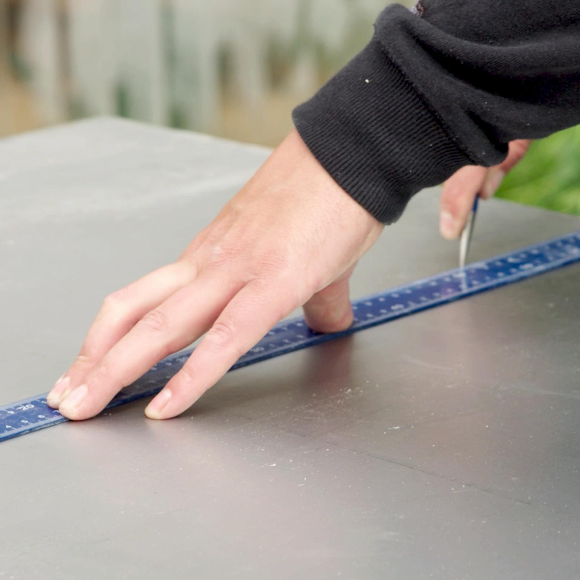 Handwerker zeichnet Maße mithilfe eines Winkels auf ein Blech.