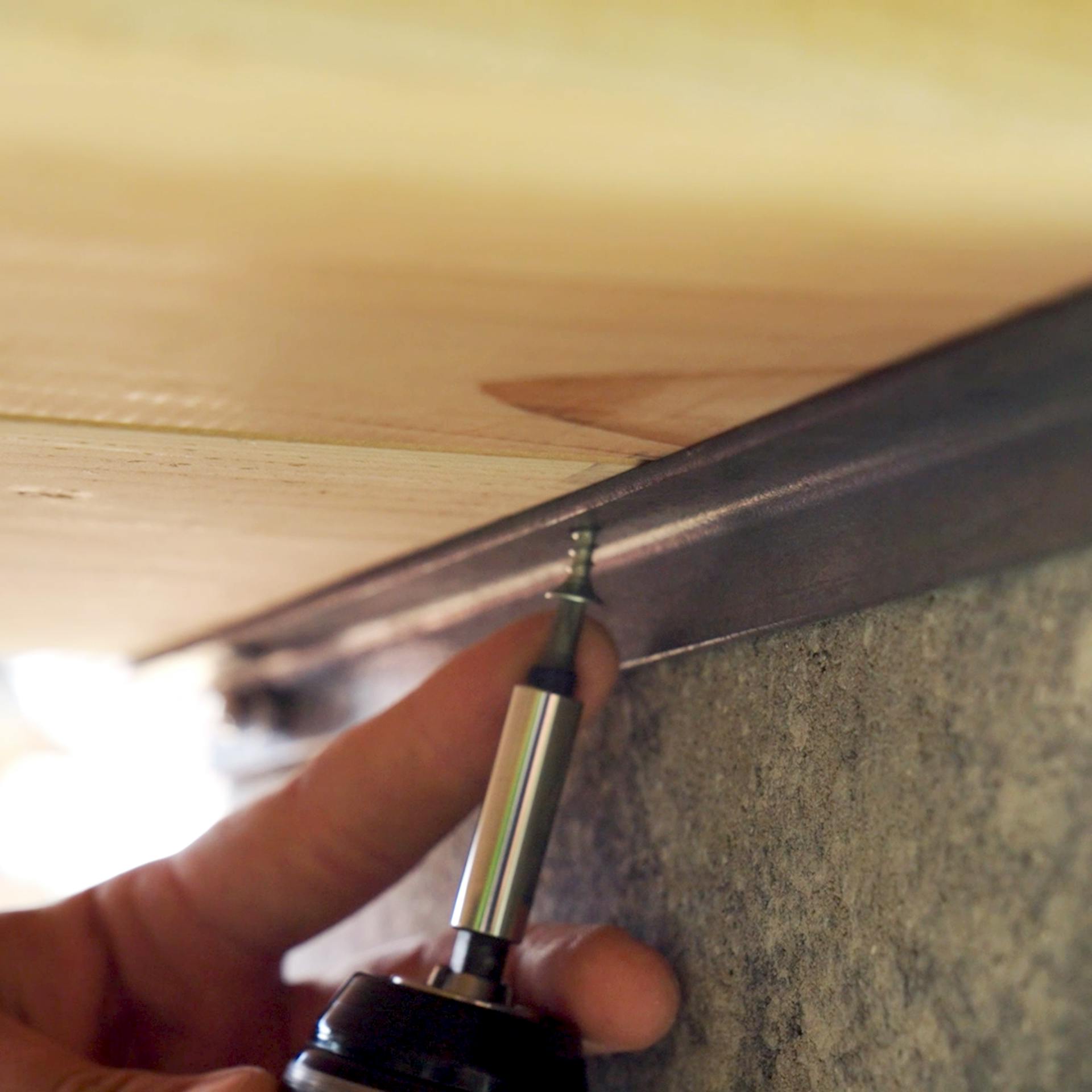 Holzbrett wird von unten mit einem Winkel befestigt.