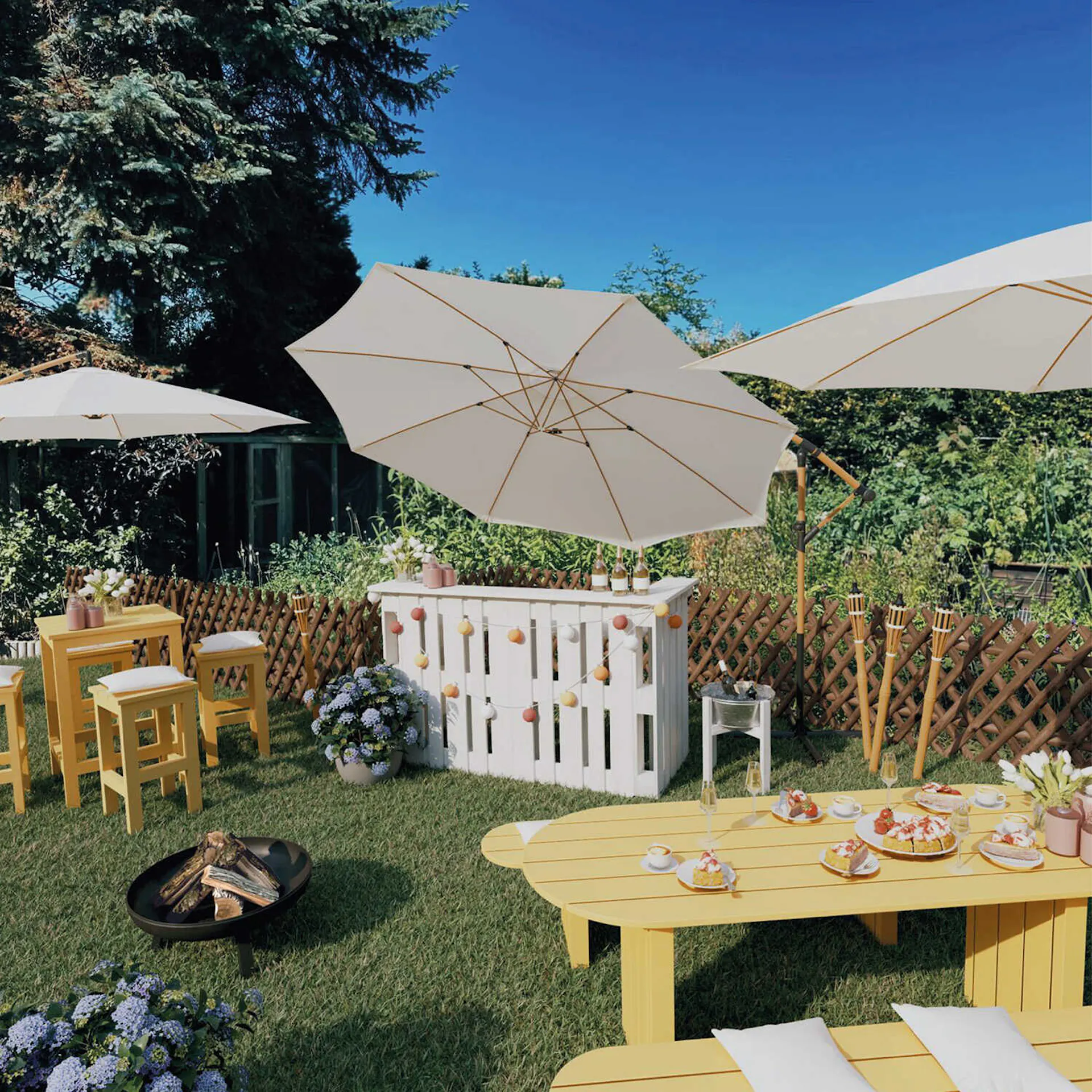 Ein Gartenparty-Bereich mit einer zentralen Theke, neben der die Sitzgruppe Ede Quadratisch steht. Davor steht eine Feuerschale der Gartentisch Emilia mit Sitzbänken.