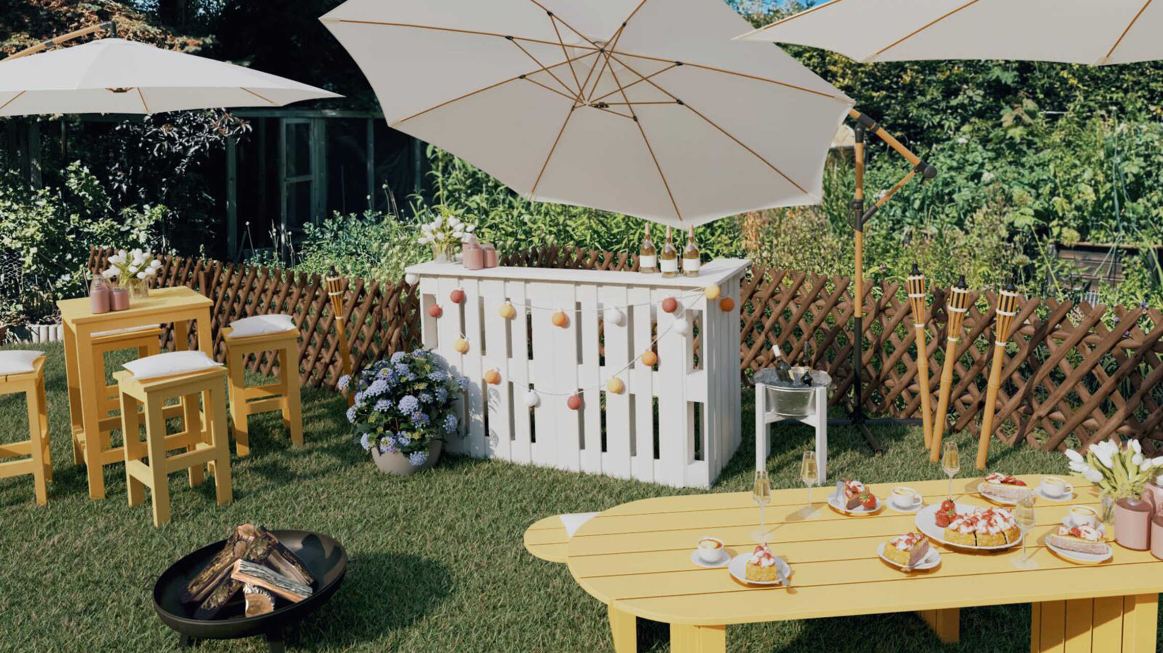 Ein Gartenparty-Bereich mit einer zentralen Theke, neben der die Sitzgruppe Ede Quadratisch steht. Davor steht eine Feuerschale der Gartentisch Emilia mit Sitzbänken.