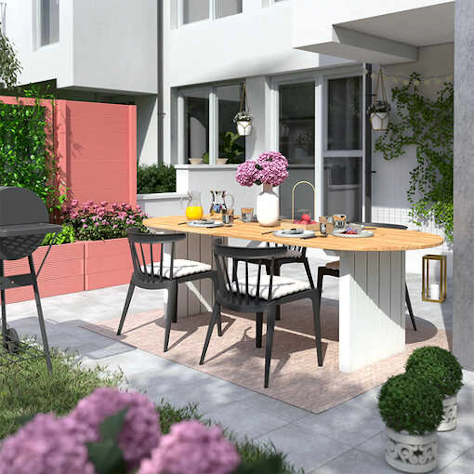 Gartentisch Emilia steht auf einer hellen Terrasse, wo das Hochbeet Alfred in einem pastellrot als Sichschutz aufgestellt worden ist.
