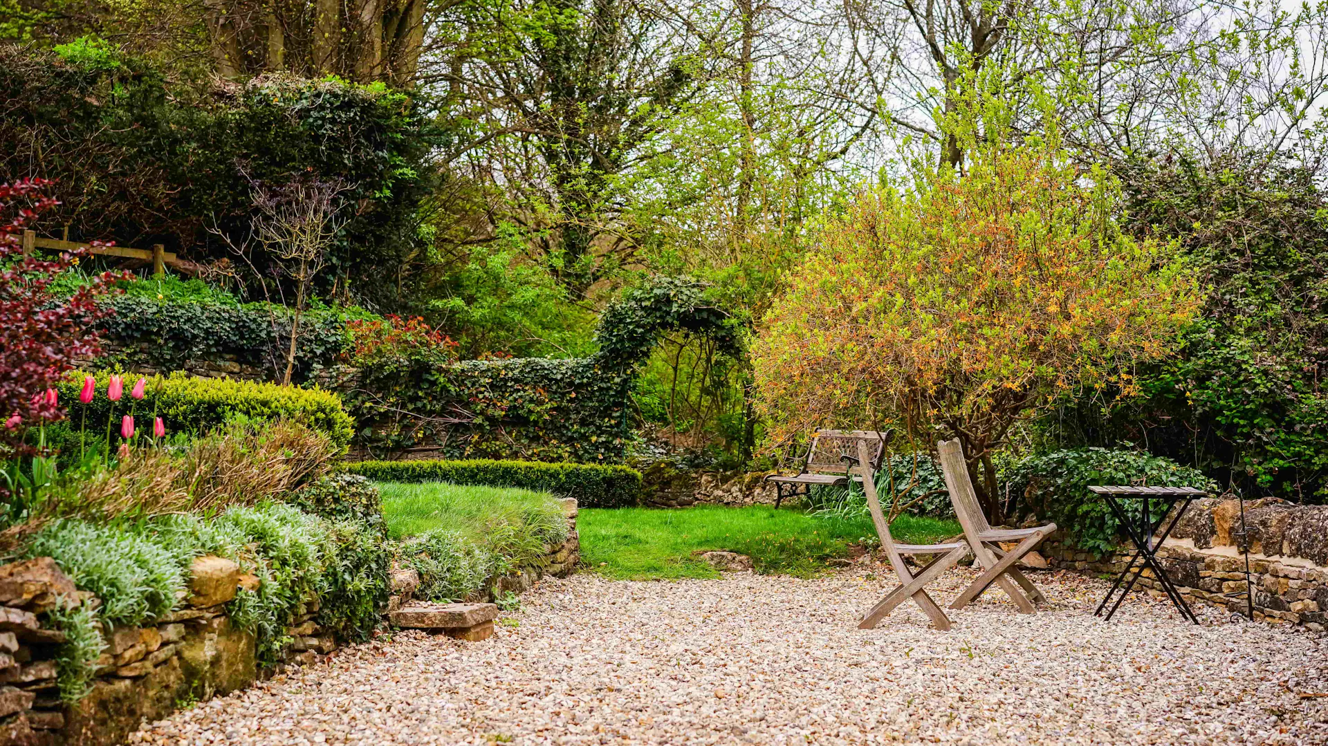 Sitzecke bestehend aus Holzstühlen und Holztisch in einem englisch angelegten Garten