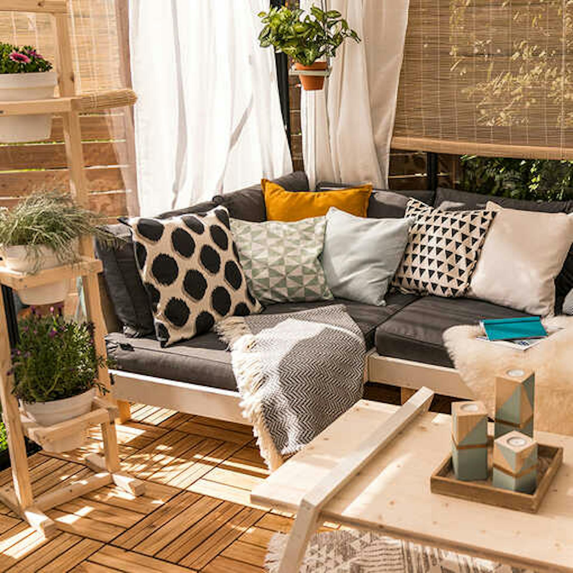 Loungemöbel Kiluja auf einer gemütlichen Terrasse mit Pflanzbank Flora und Couchtisch Philip.