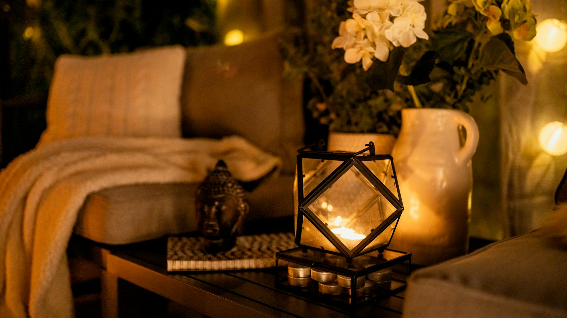 Gemütliche Sitzecke im Garten am Abend mit Laterne, Dekoration und Decken
