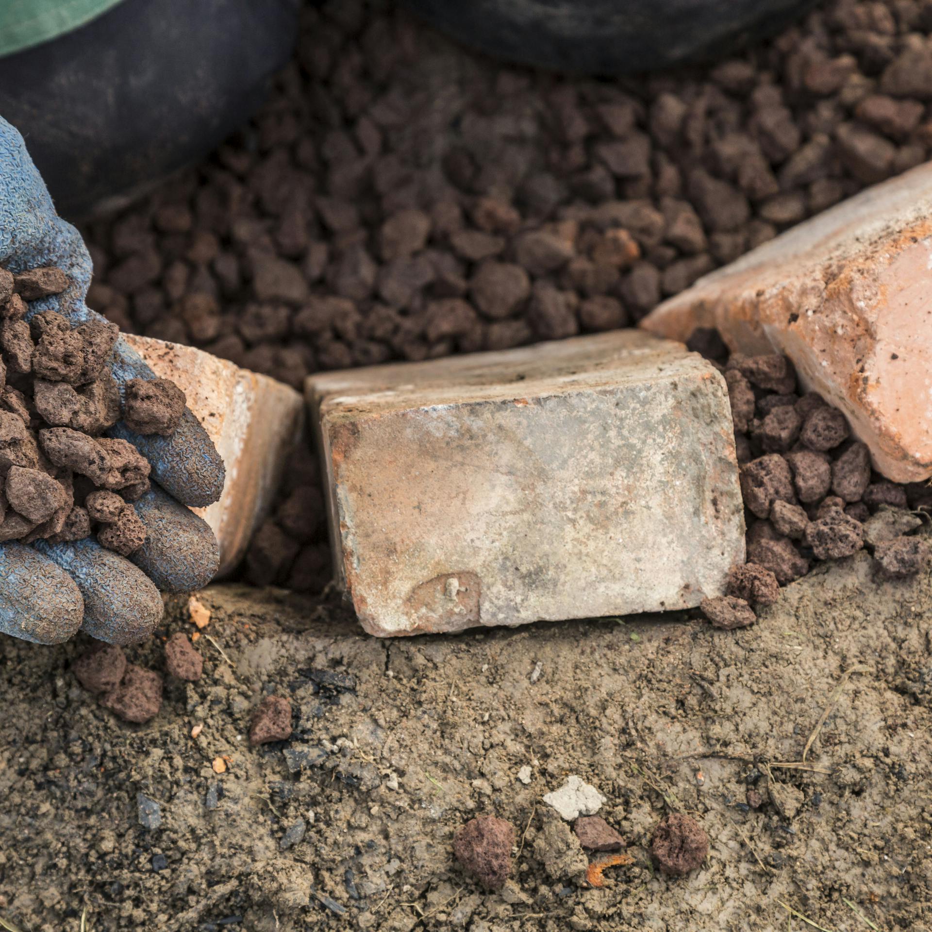 Person füllt Lava-Mulch in Feuerstelle.