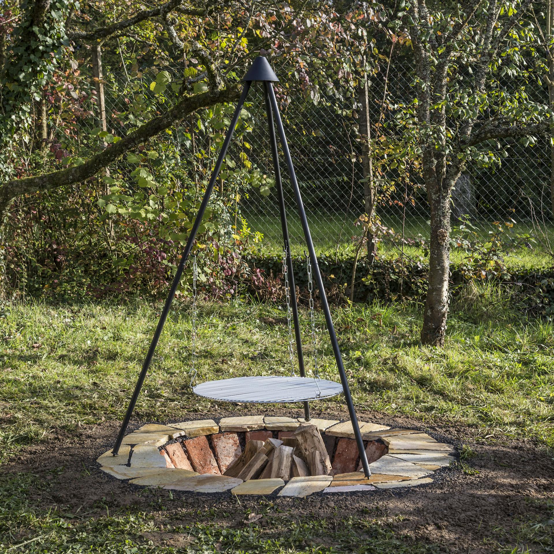 Schwenkgrill über einer Feuerstelle in einem Garten