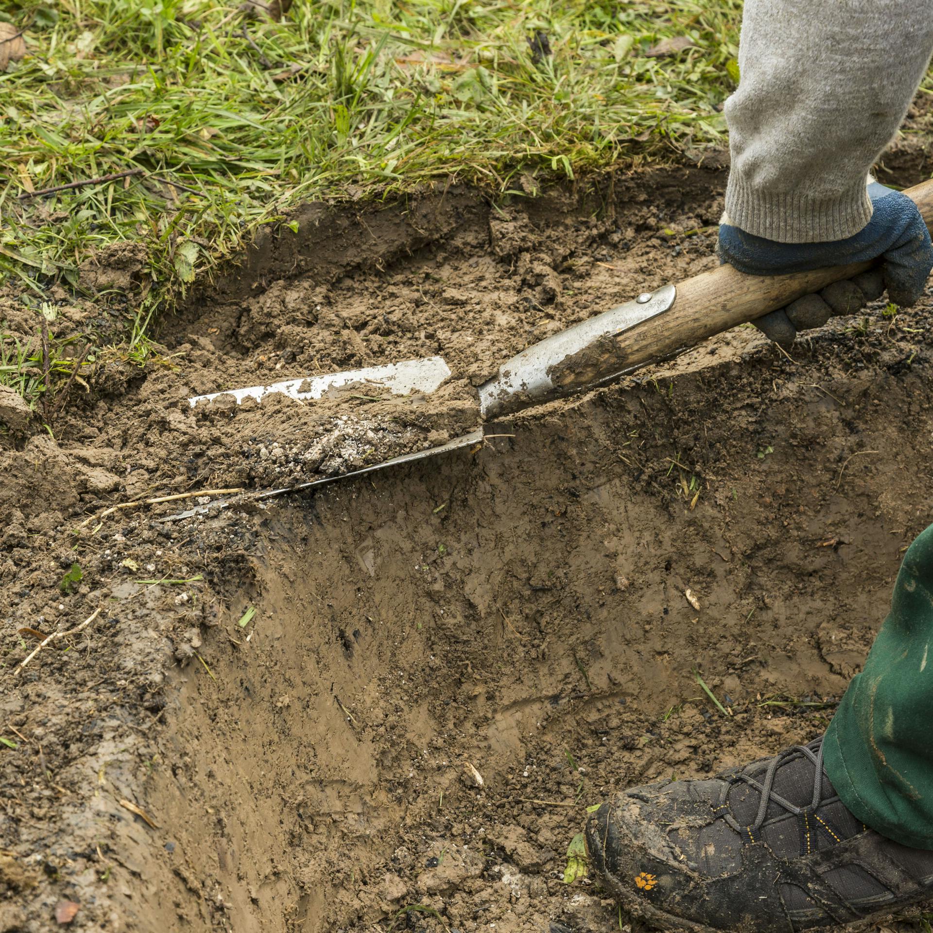Person hebt Loch für die Feuerstelle aus.