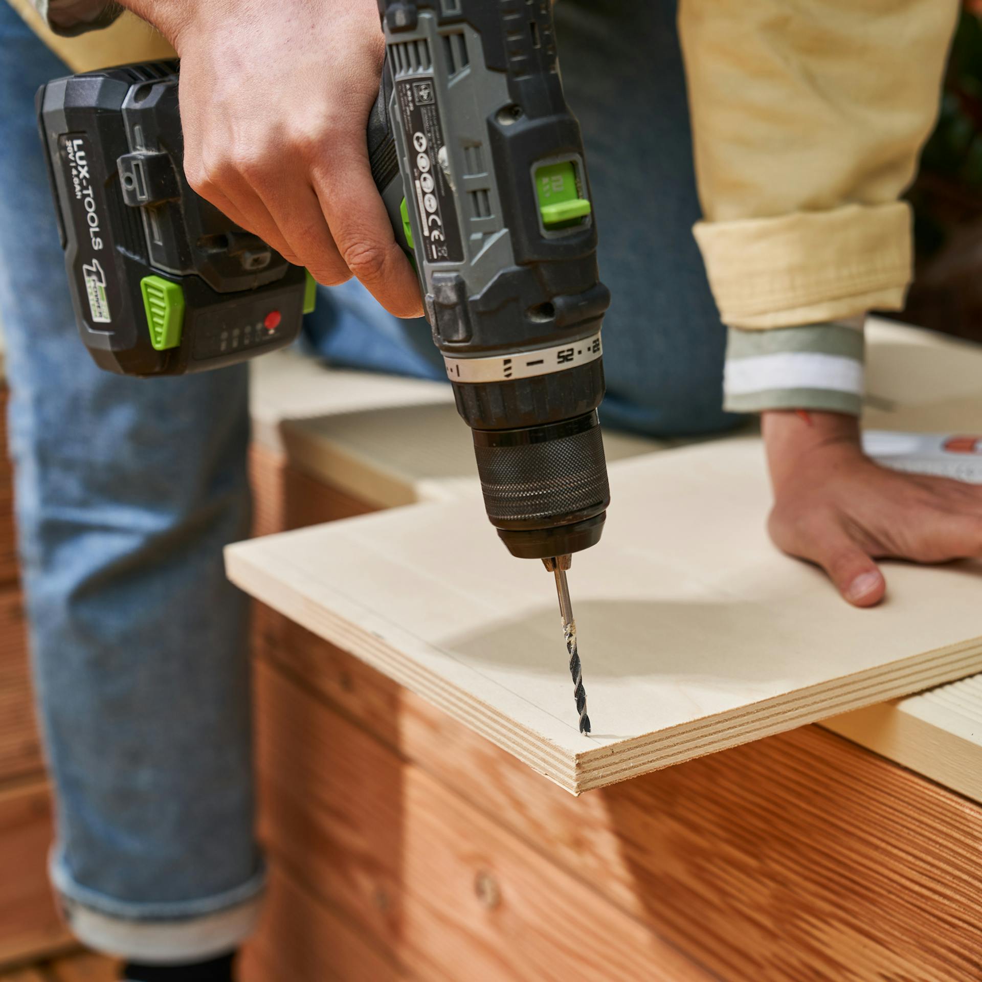 Heimwerkerin bohrt angezeichnete Löcher in Bauteil für das Becken des Fußbeckens vor.