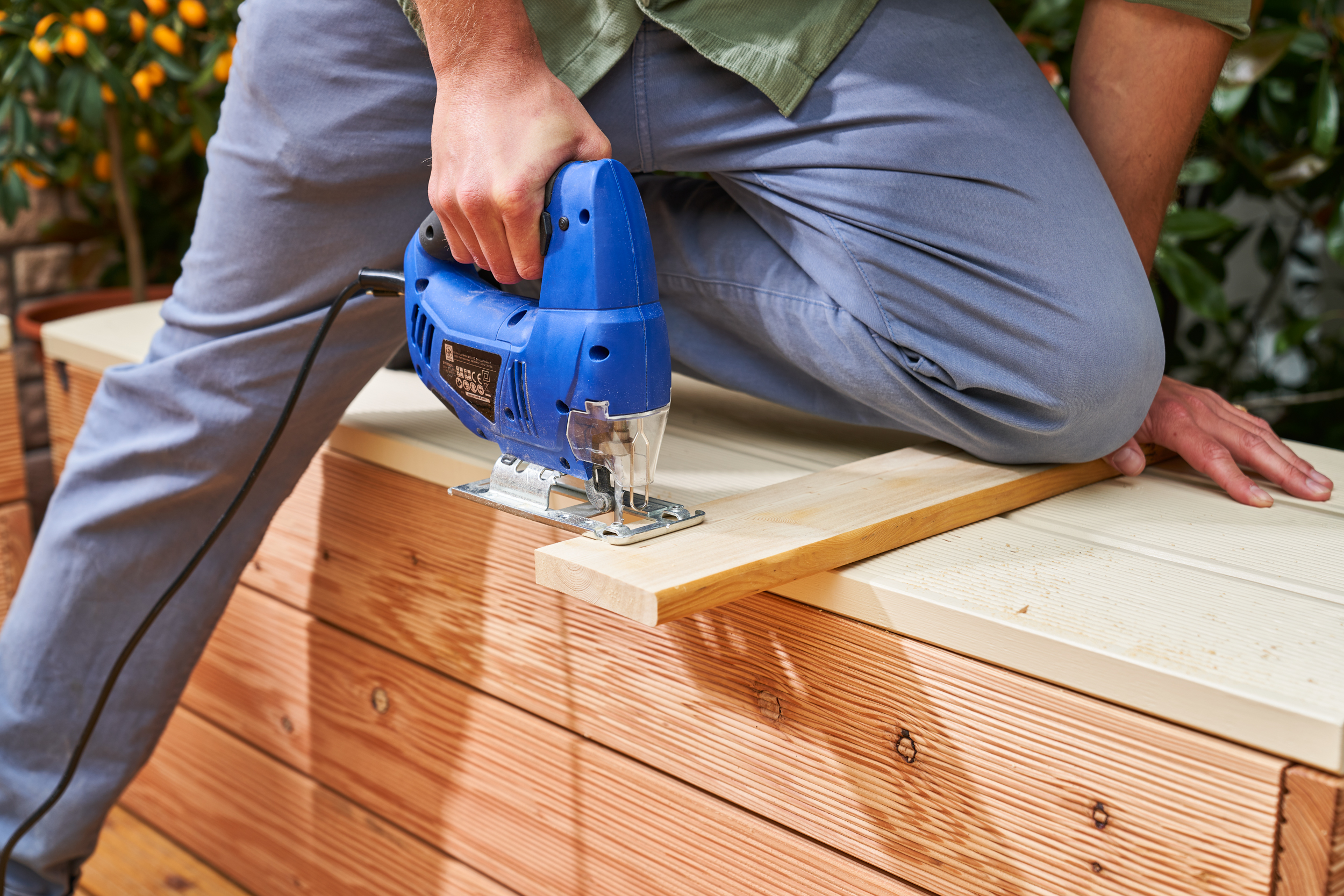 A barkácsoló dekopírfűrésszel vágja a lábfürdő burkolására szolgáló elemeket