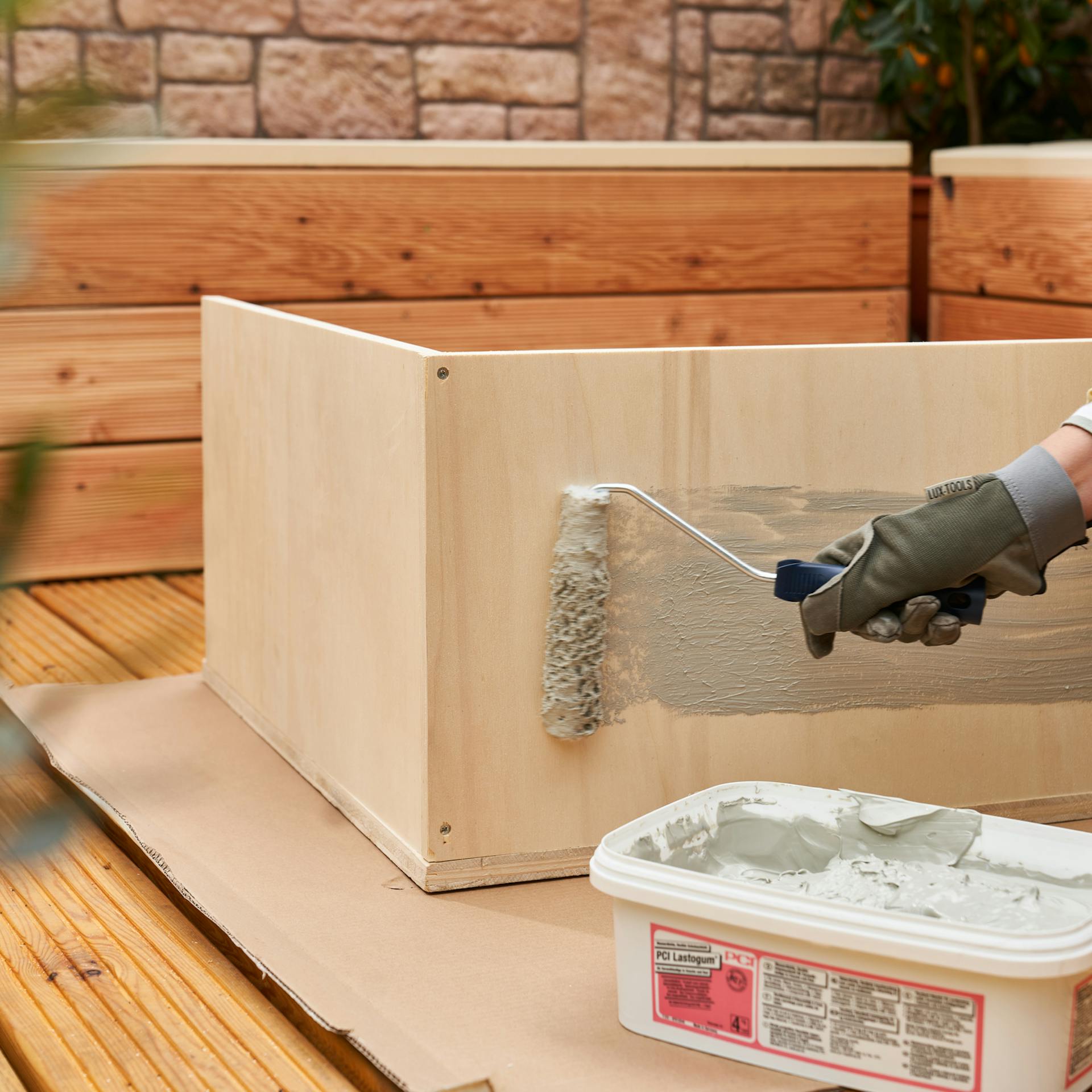 Heimwerkerin streicht das Becken mit Dichtmasse, um es abzudichten.