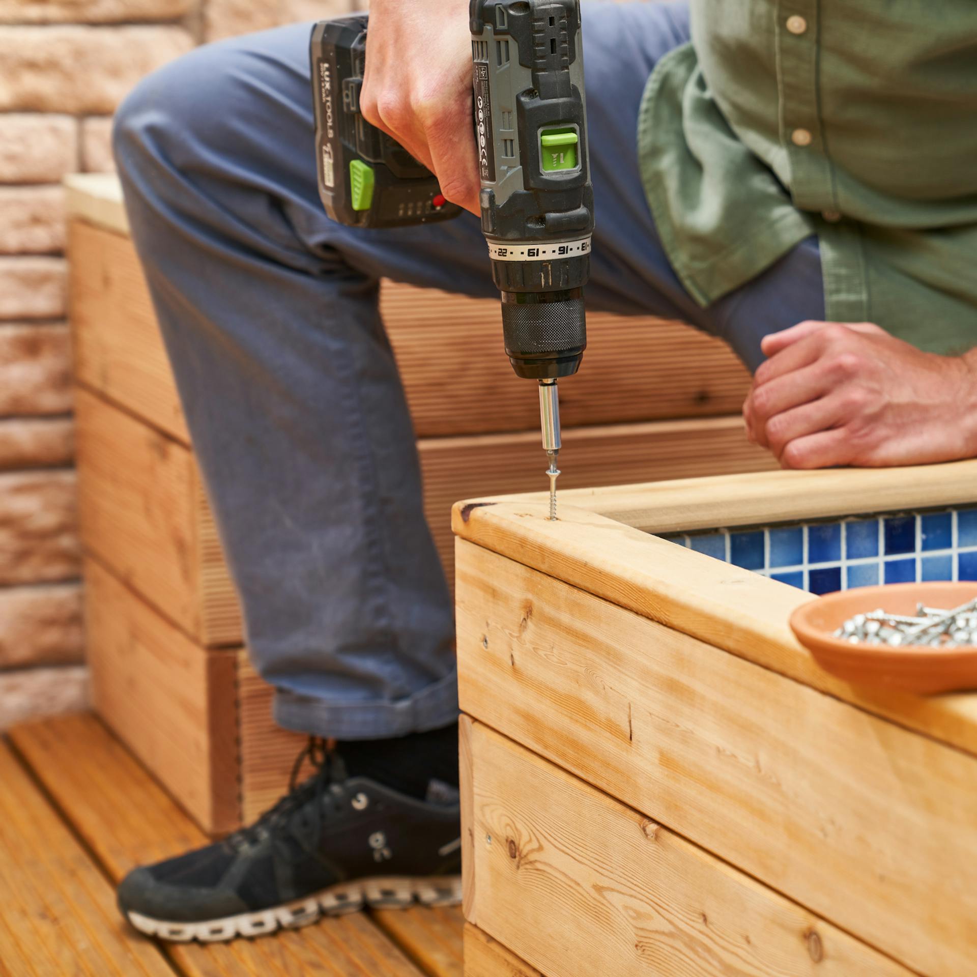 Heimwerker verschraubt Sims der Holzverkleidung des Fußbads.