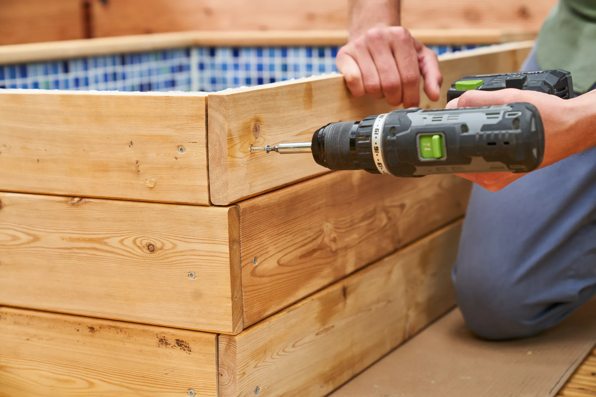 Un appassionato del fai-da-te avvita il rivestimento in legno della vasca per pediluvio.