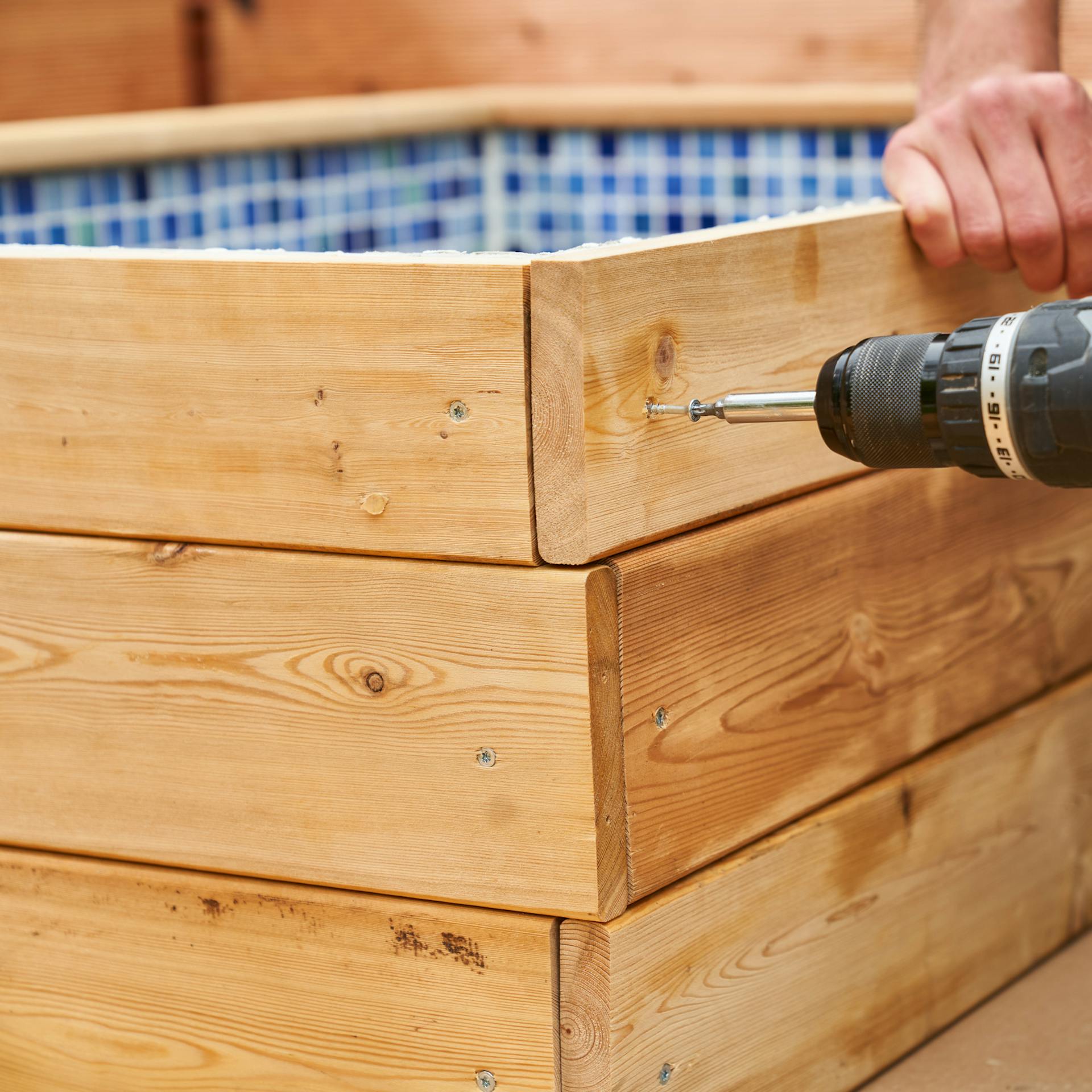 Heimwerker verschraubt Holzverkleidung des Fußbades.