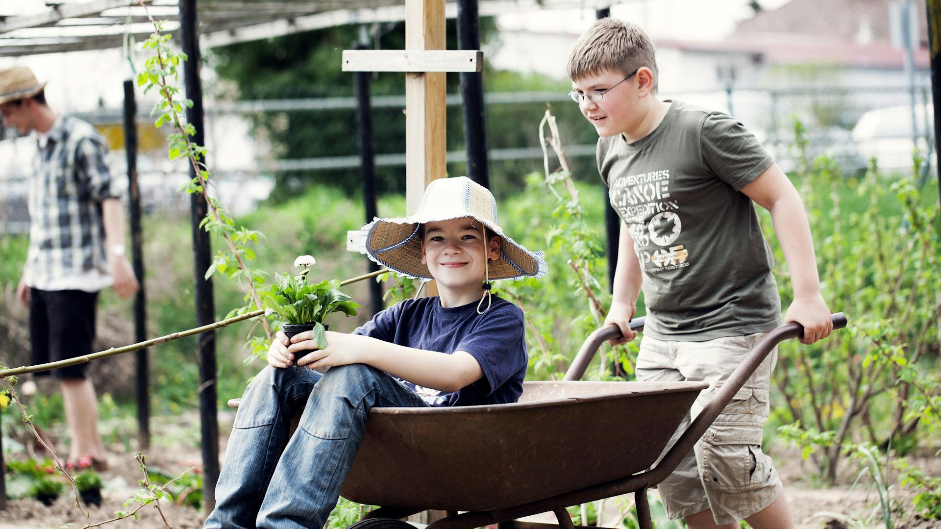Zwei Kinder mit einer Schubkarre im Garten