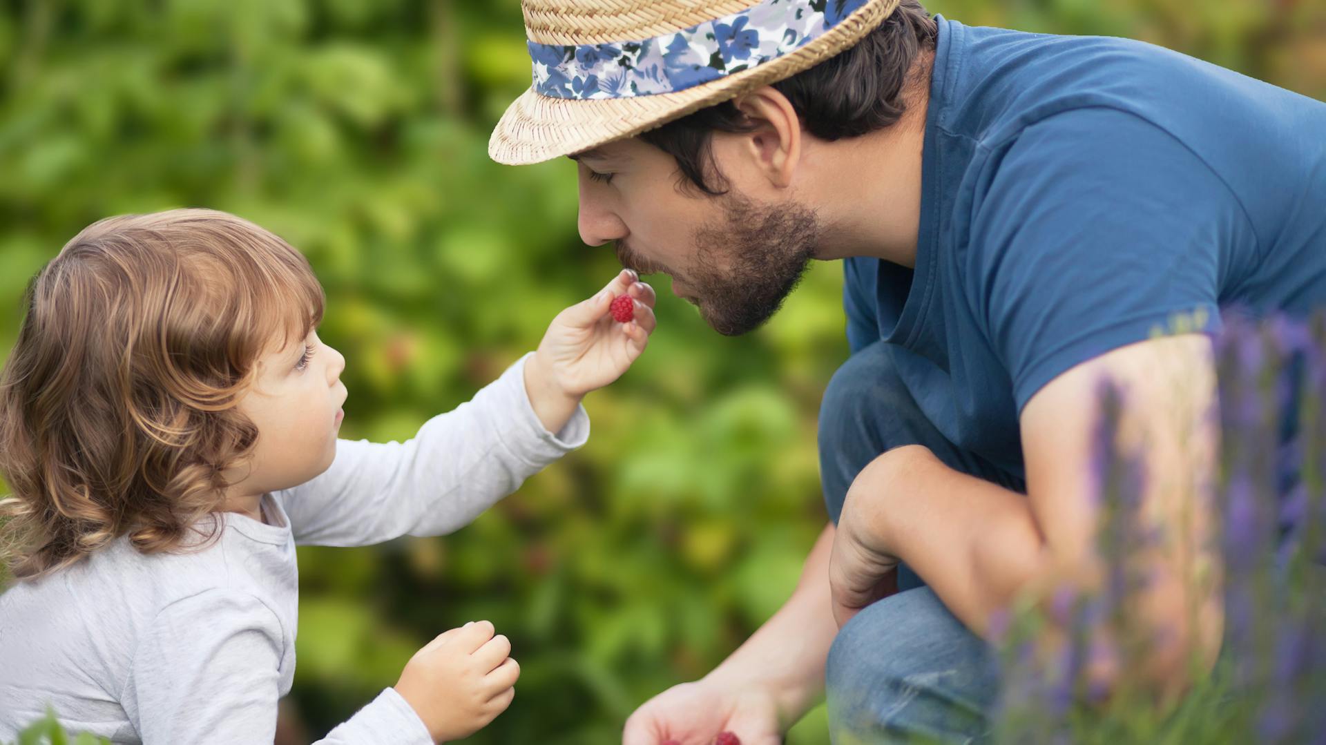 Padre e figlia mangiano bacche in giardino