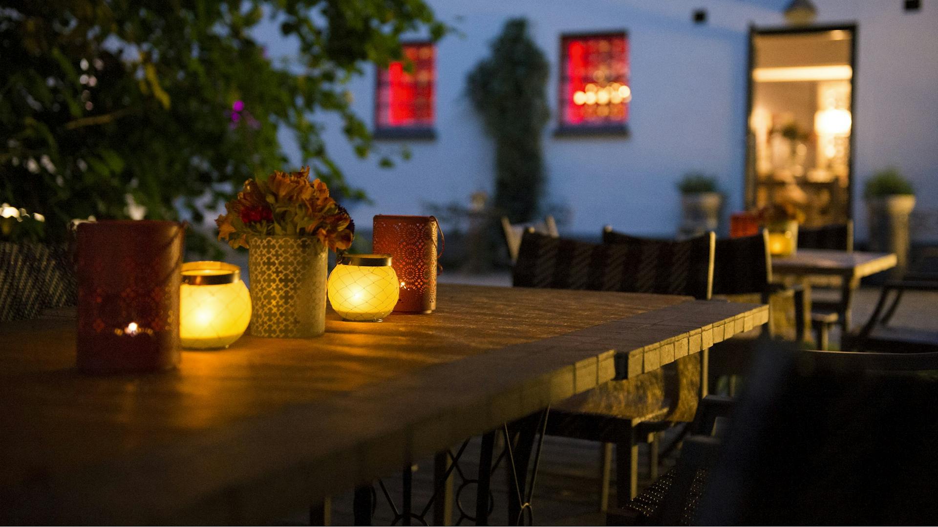 Ein Tisch steht beleuchtet im Garten bei Nacht.
