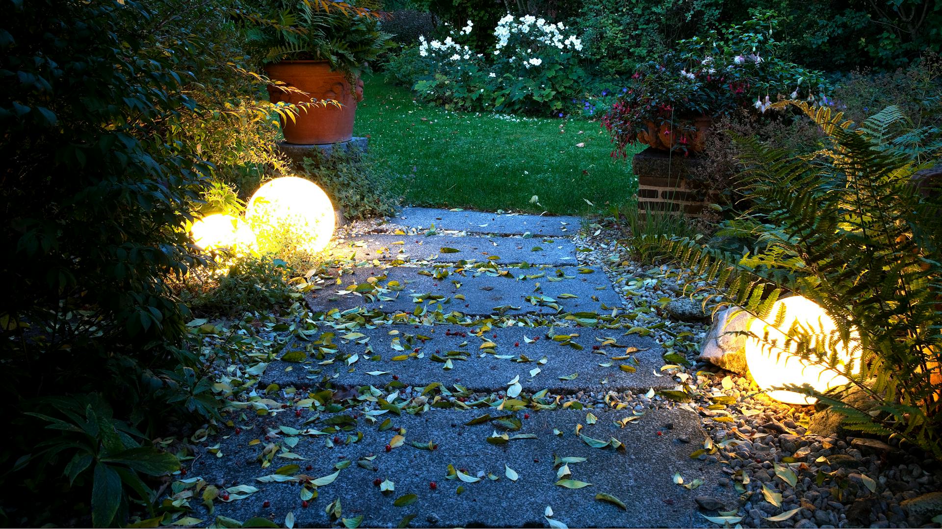 Due grandi lampade in giardino illuminano un vialetto.