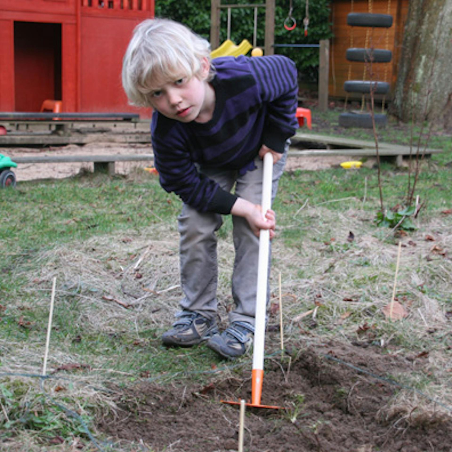 Kind legt ein Beet im Garten an.