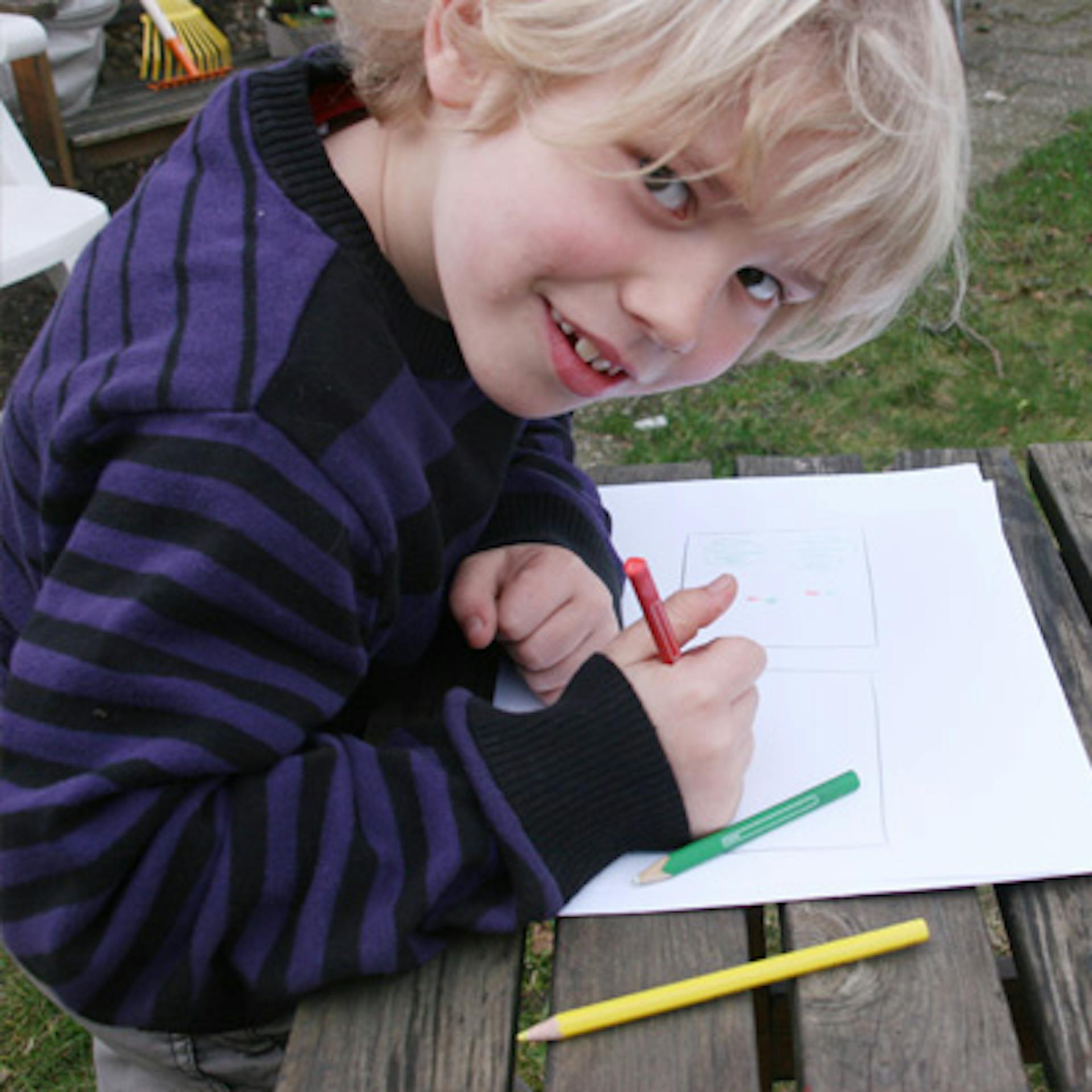 Un bambino progetta un’aiuola in giardino con pennarelli e carta.