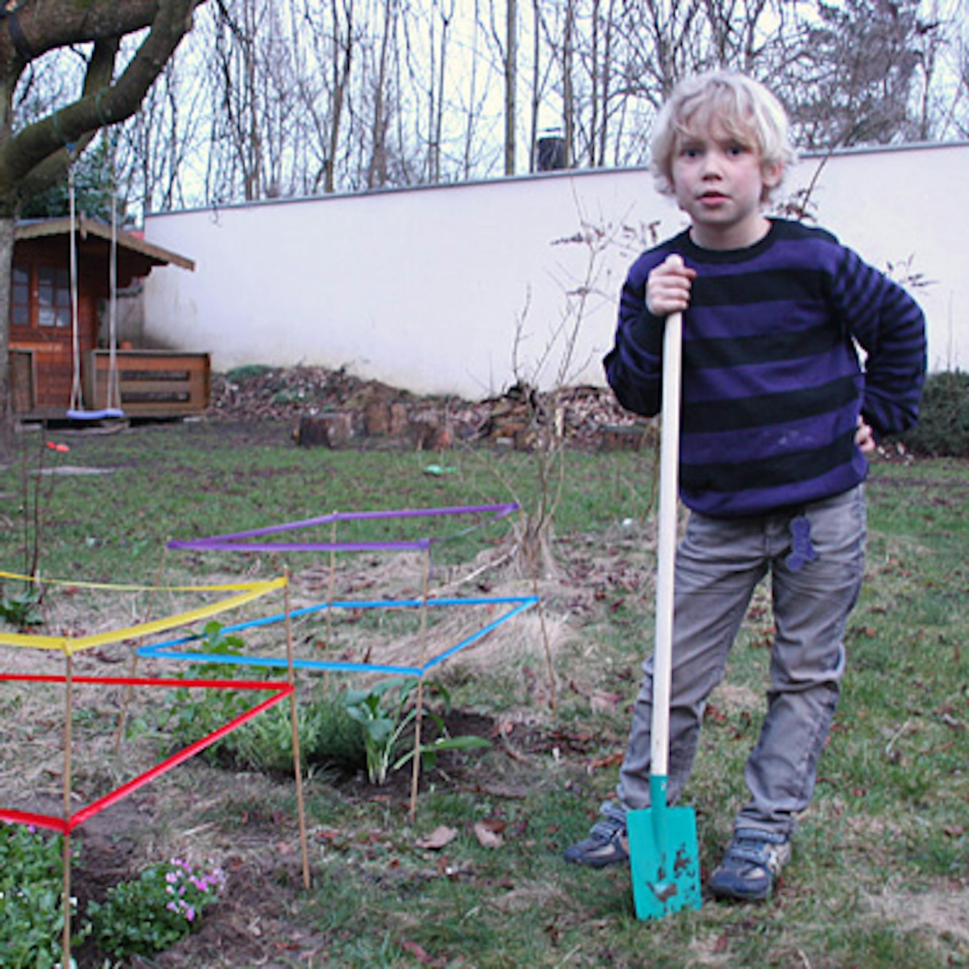 Un bambino con una pala per bambini davanti all’aiuola per bambini appena realizzata.
