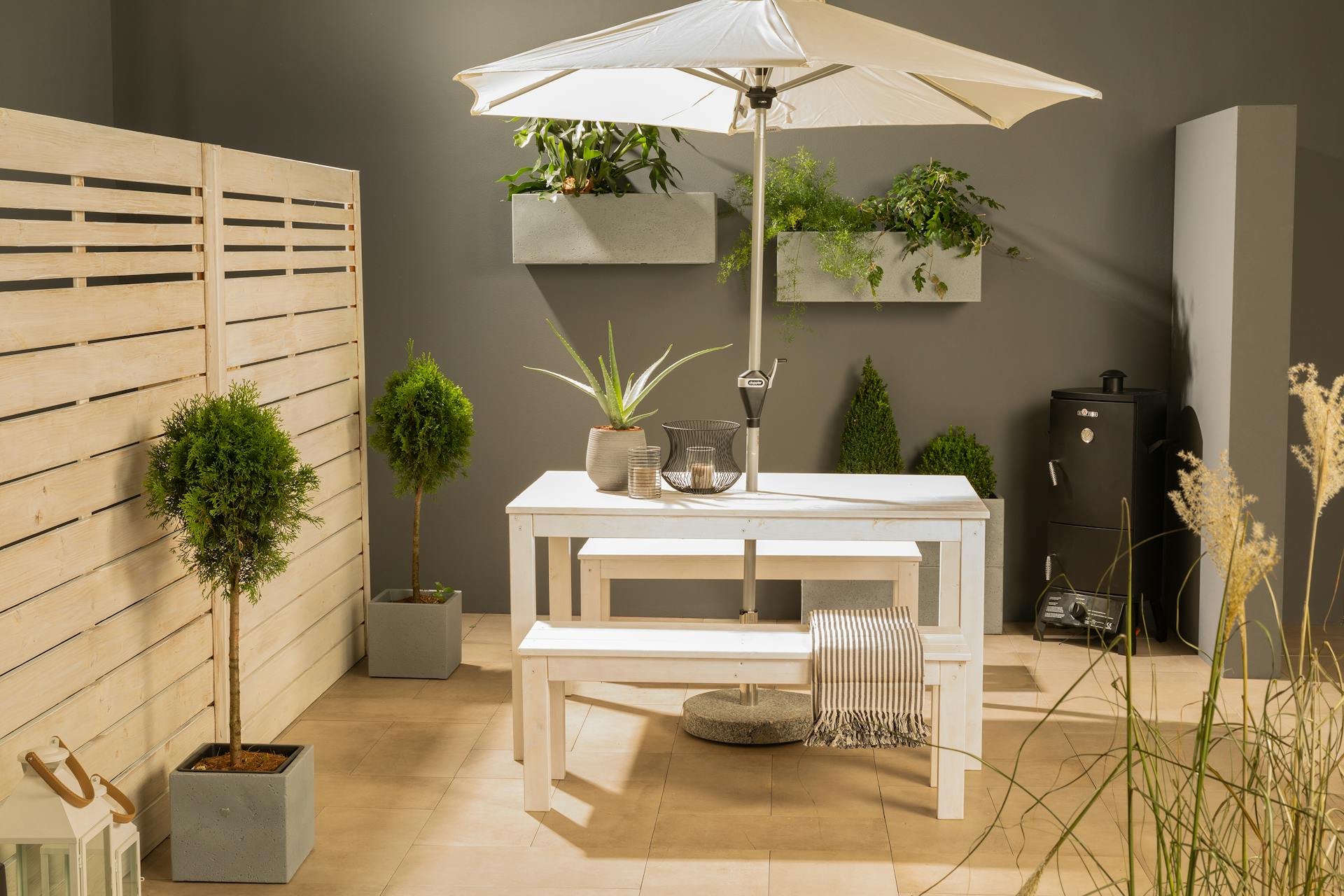 Gartentisch Sophie steht mit zwei weißen Gartenbänken Sophie auf einer Terrasse.