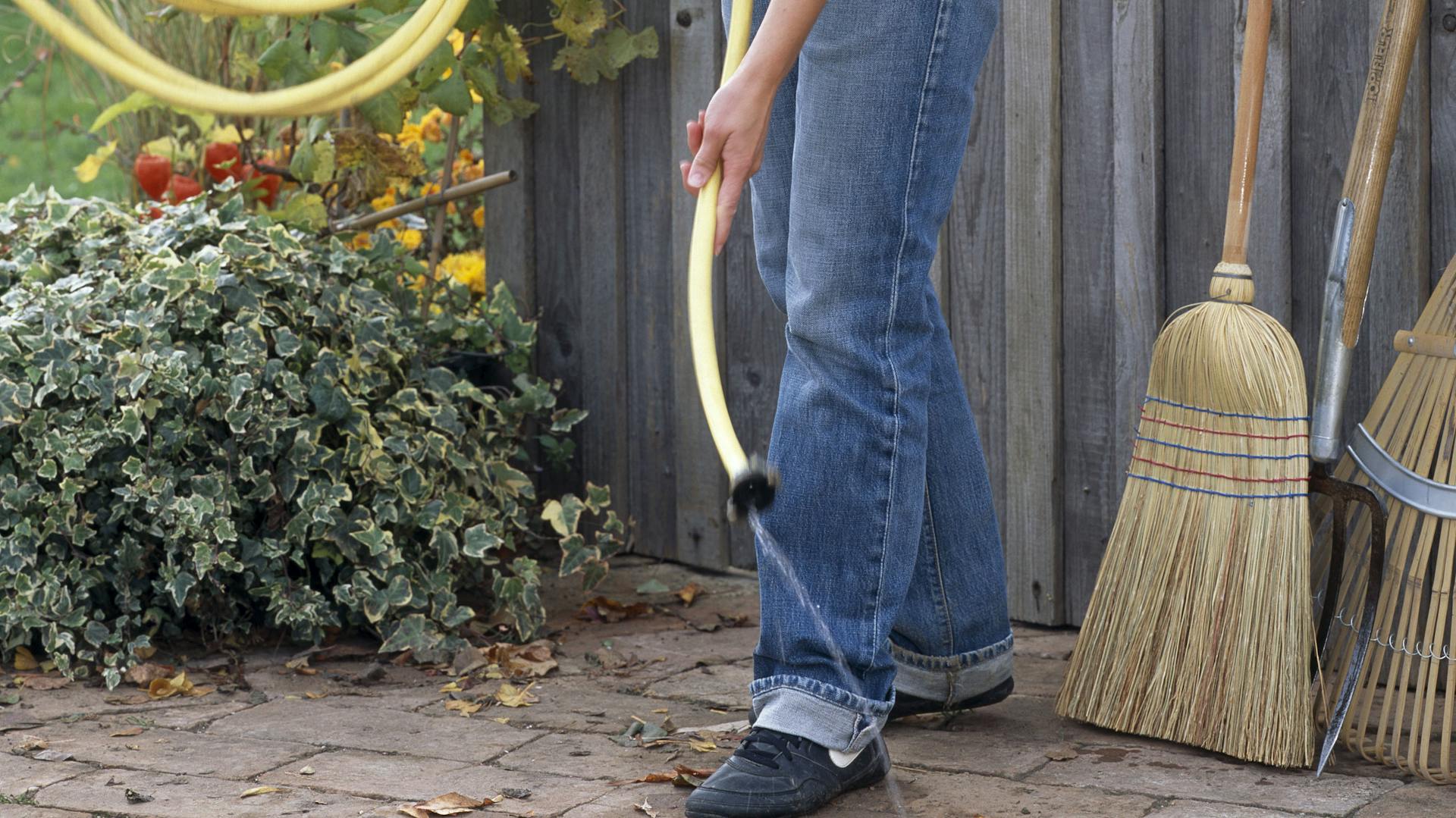Eine Frau leert einen Gartenschlauch aus.