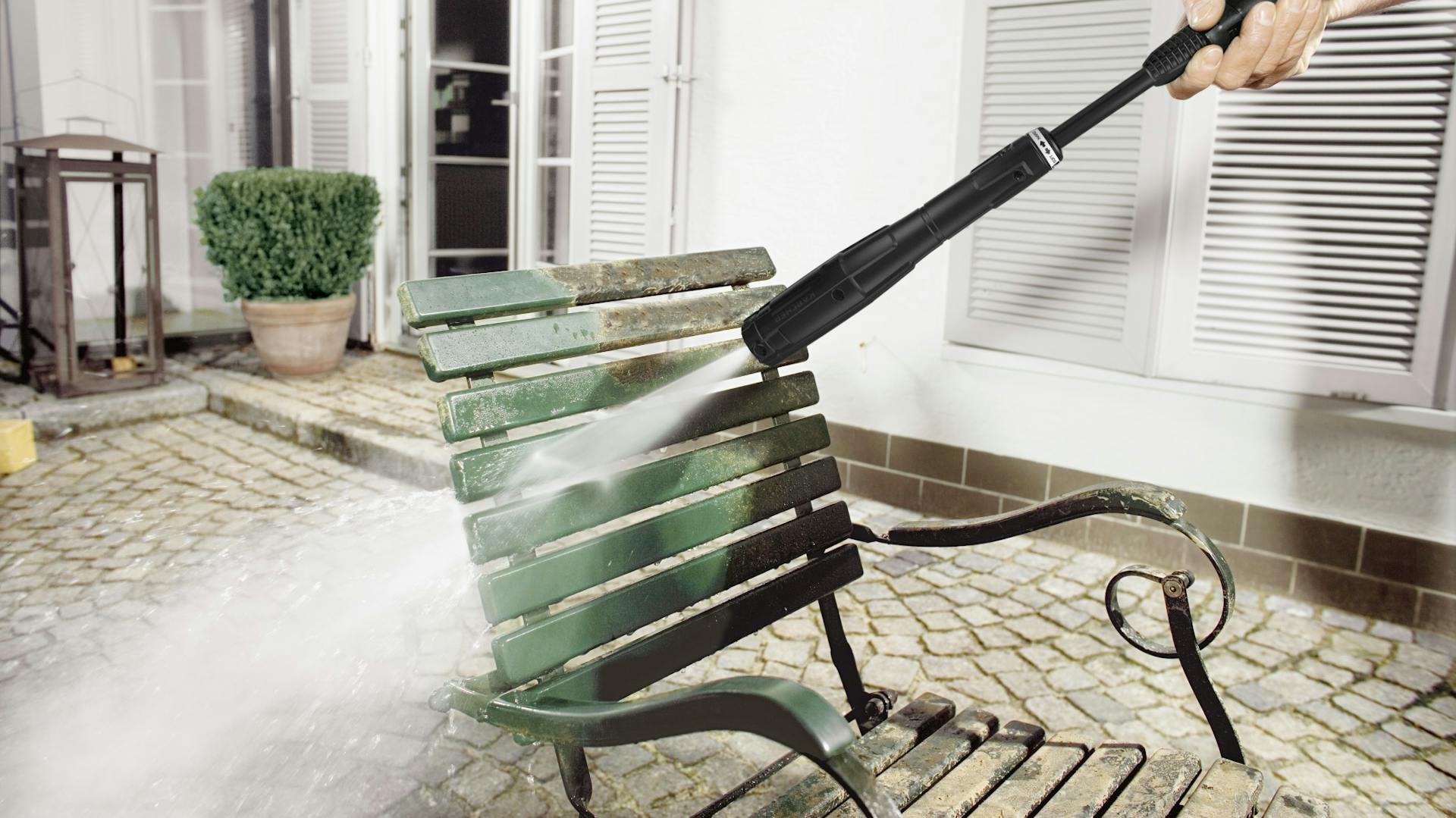 Absprengen von grobem Dreck von grün lackiertem Stuhl aus Holz und Metall mit Hochdruckreiniger