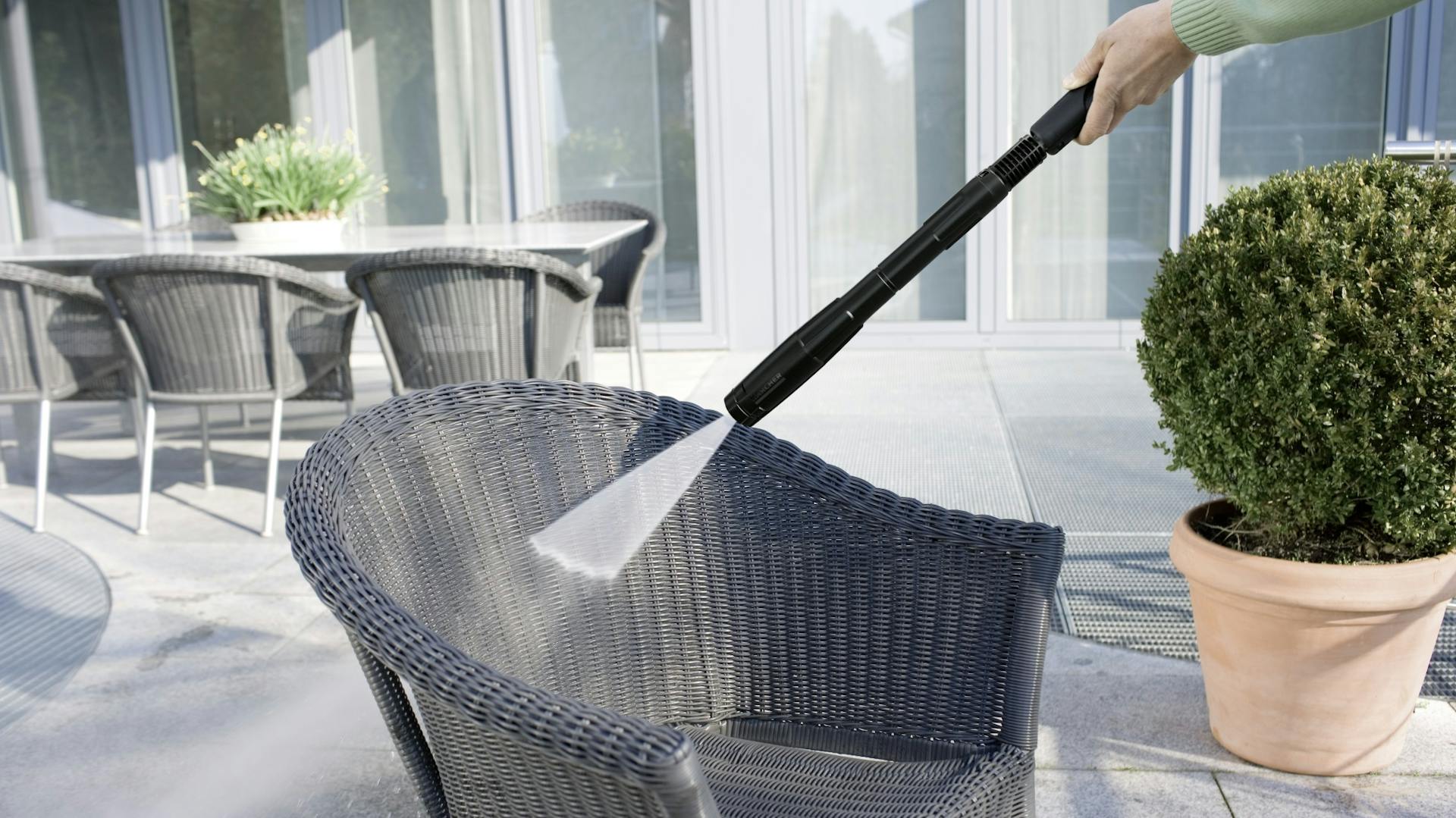 Reinigung eines Loungesessels für den Garten mit Hochdruckreiniger auf Terrasse