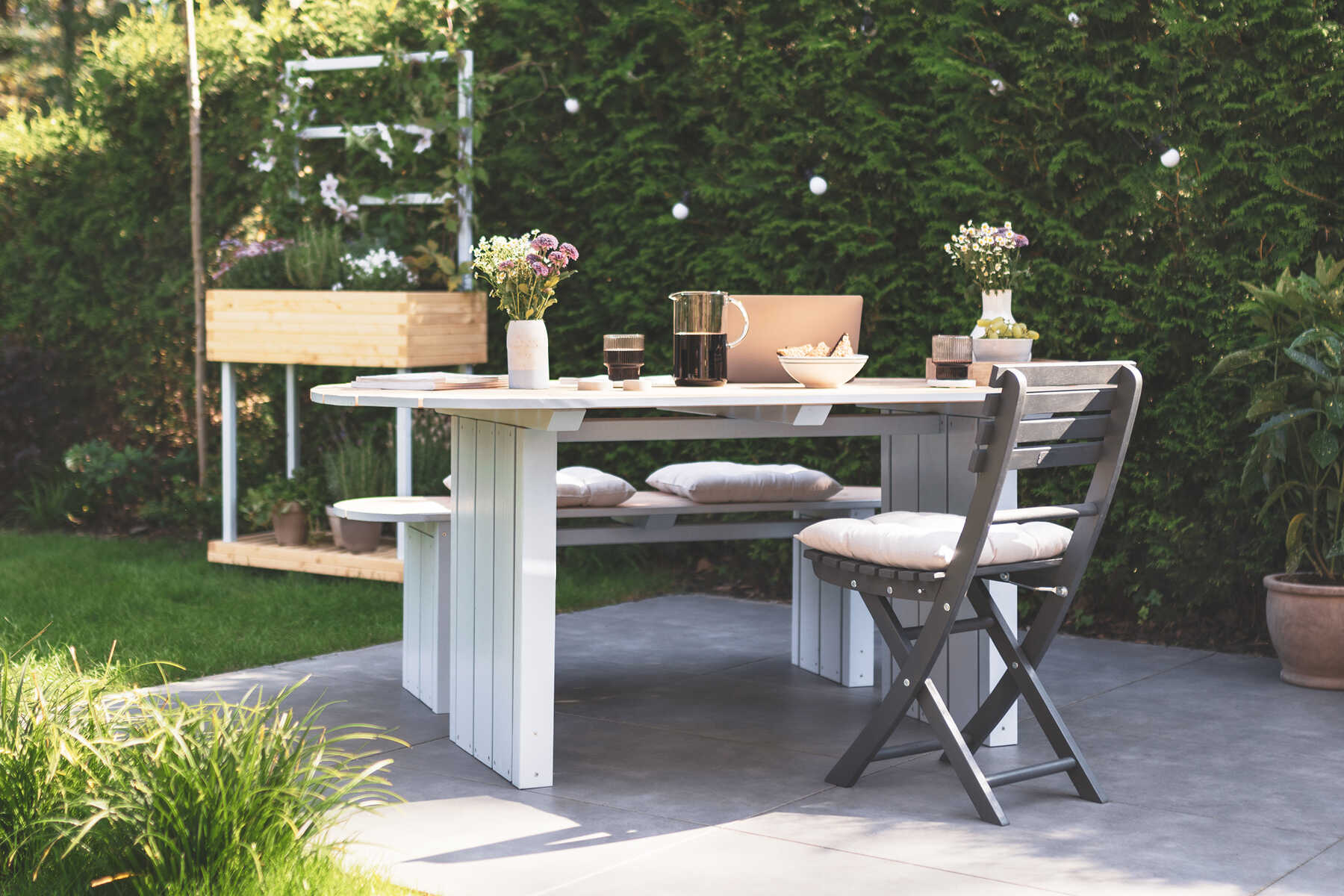 Gartentisch Emilia steht auf der Terrasse und ist mit Blumen dekoriert.