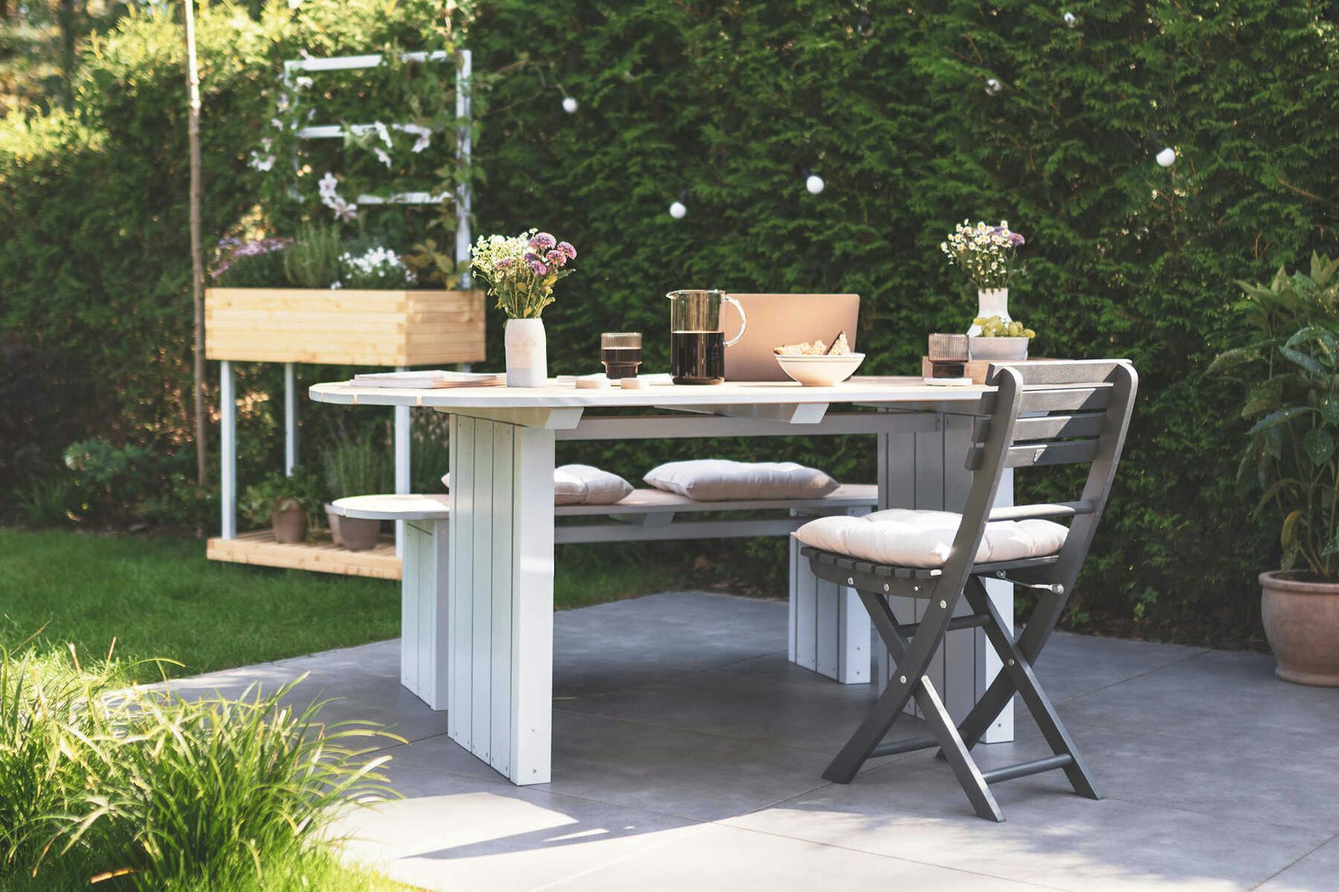 Gartentisch Emilia steht auf der Terrasse und ist mit Blumen dekoriert.