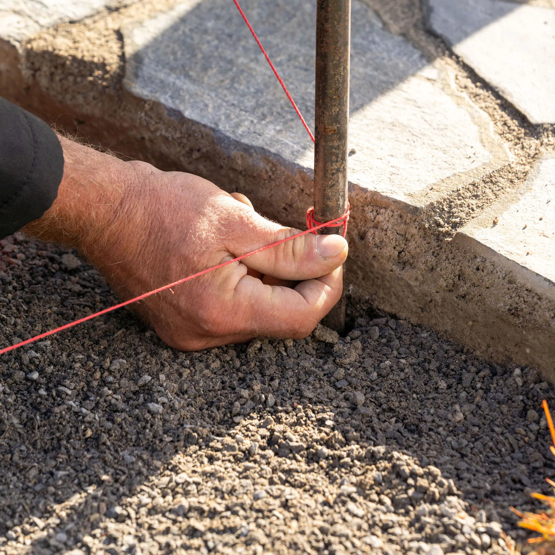 Jedna ruka zauzluje provázek na kolík.