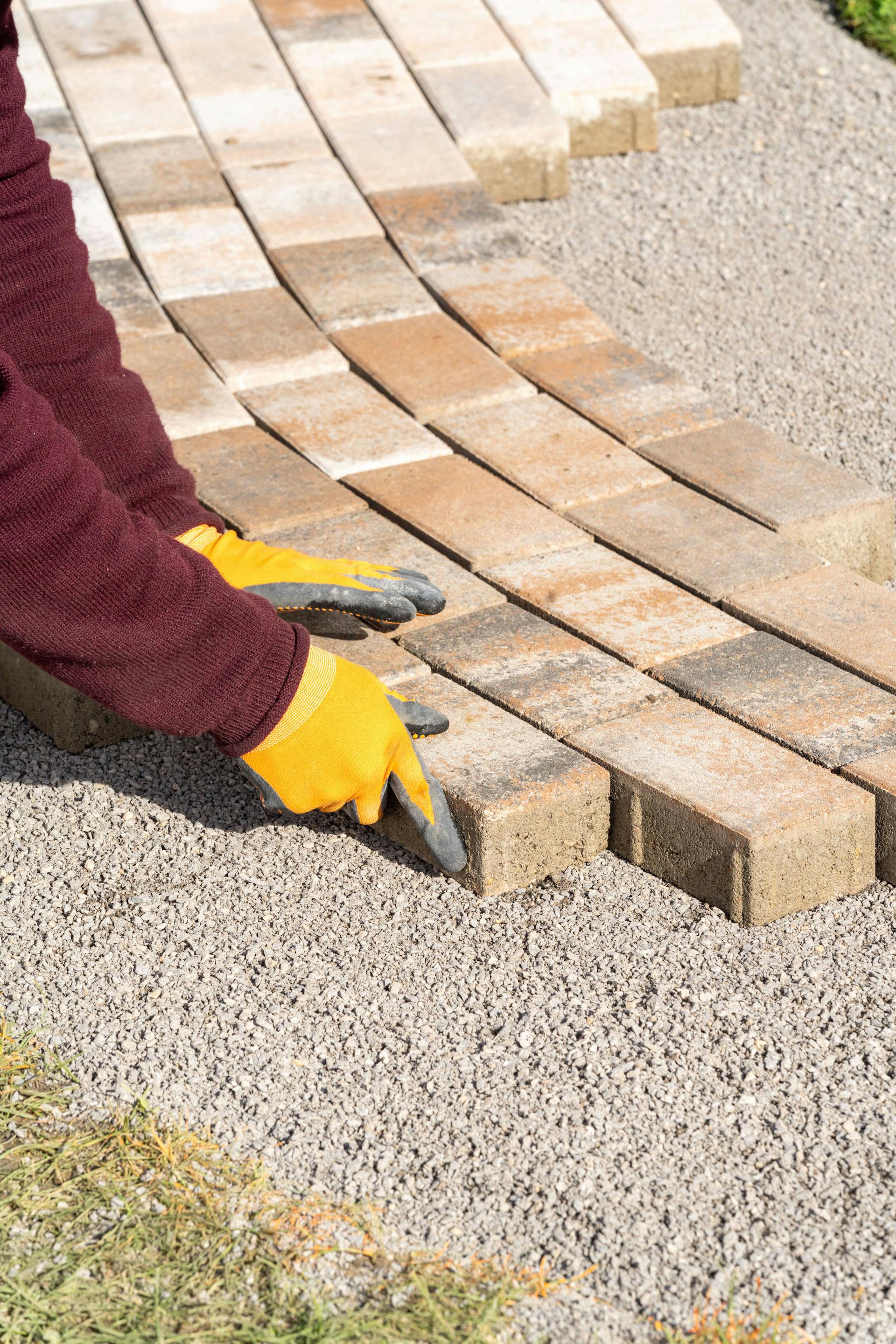 Mani posano un selciato su un letto di pietrisco